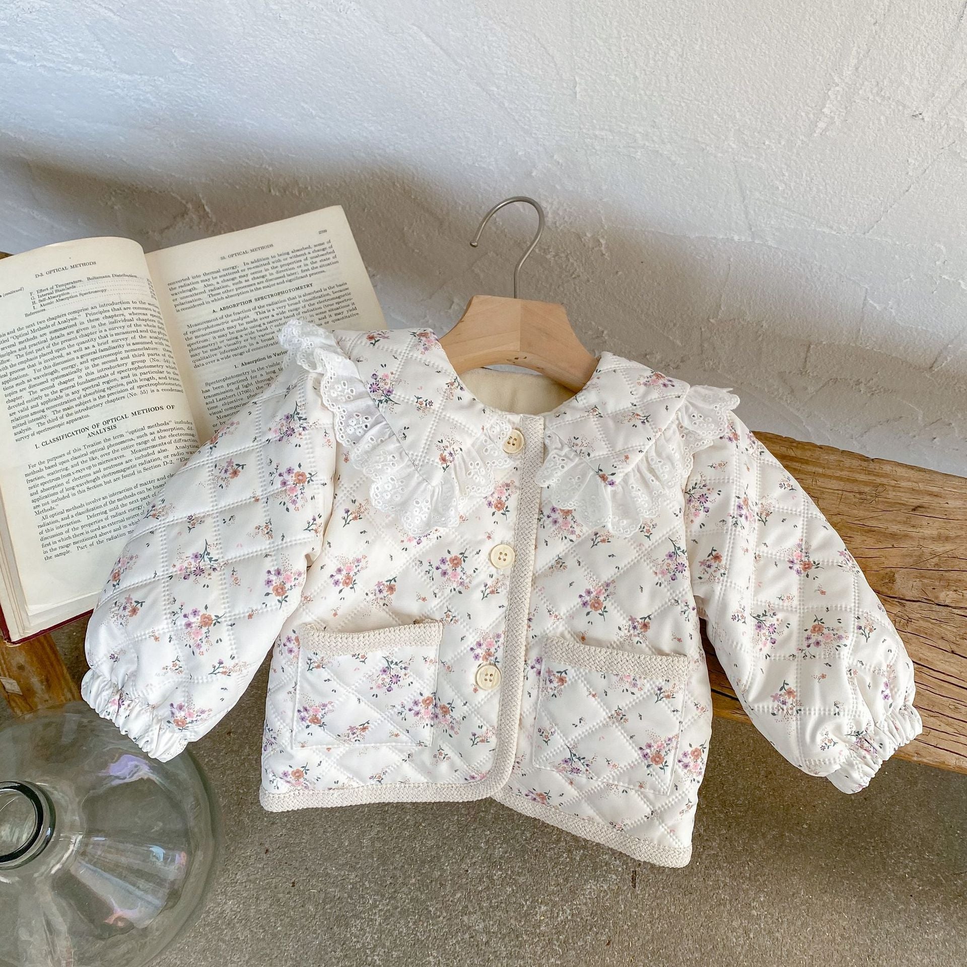 Baby girl winter coat with floral pattern, round lace collars, and pockets, designed for warmth and style.