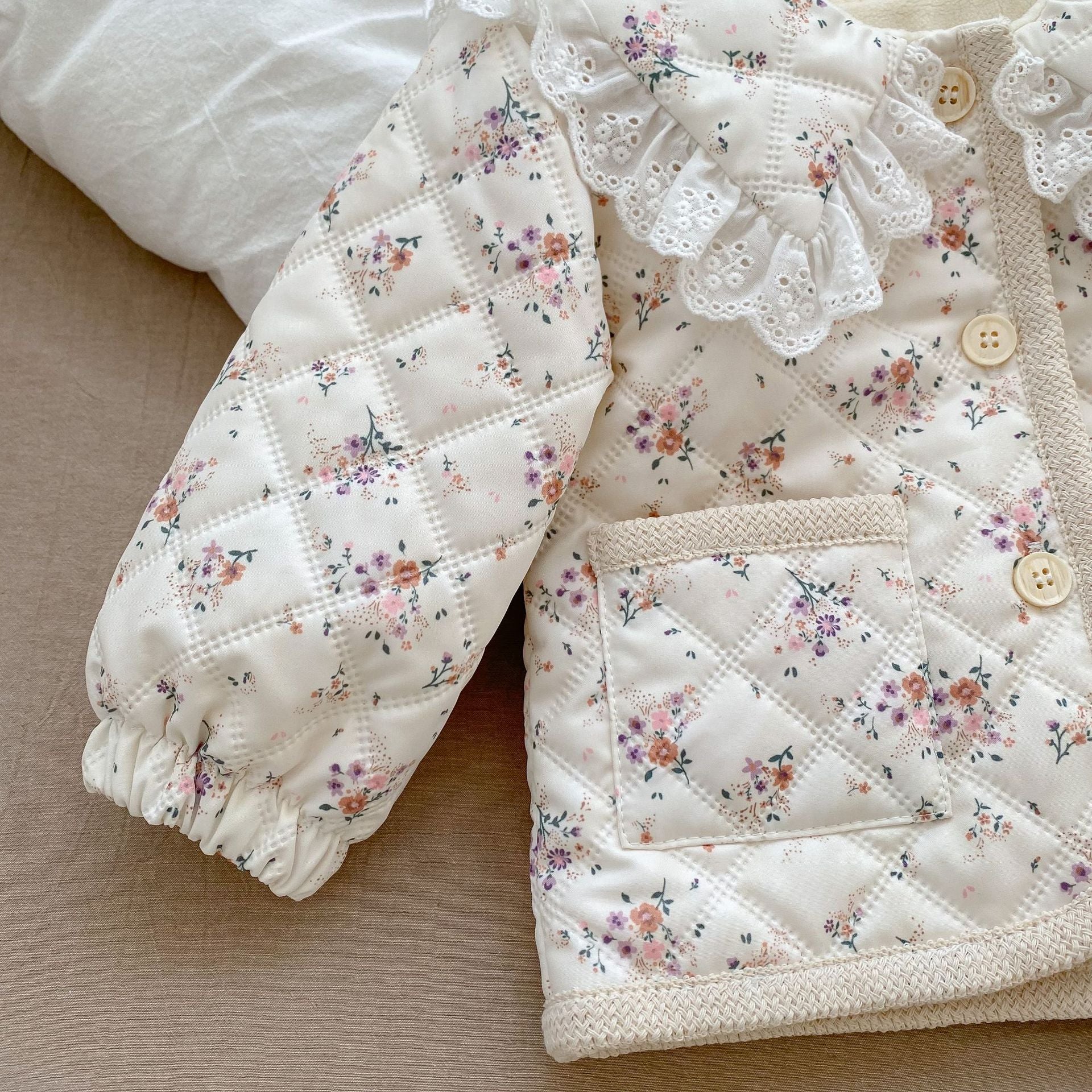 Baby girl winter coat with floral pattern, round lace collars, and pockets, designed for warmth and style.