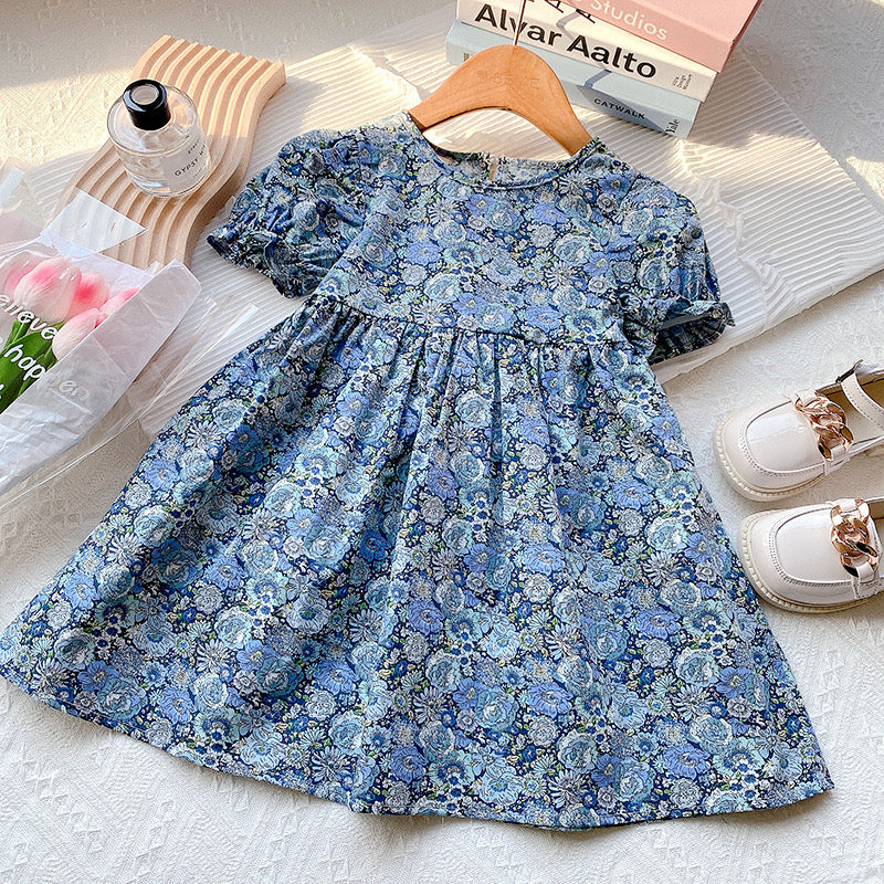 A beautiful baby girl dress featuring floral embroidery and lace patchwork, designed with puff sleeves and a backless silhouette in blue.