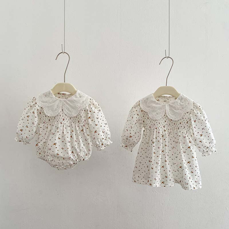 Baby girl wearing a floral pattern doll neck onesie and dress in white and beige, showcasing a cute and stylish design.