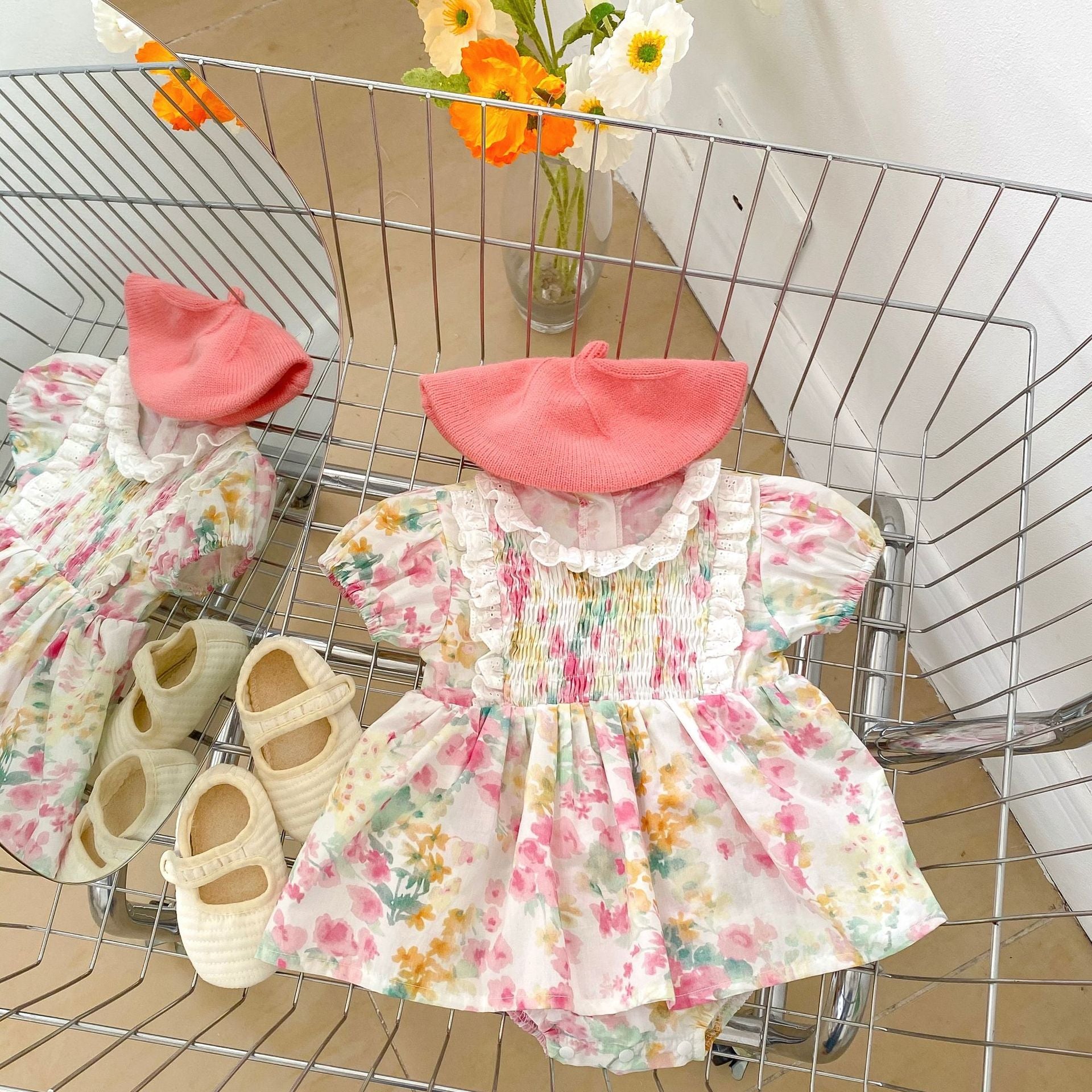 A baby girl wearing a floral pattern loose summer onesies dress in pink, showcasing a charming design perfect for warm weather.