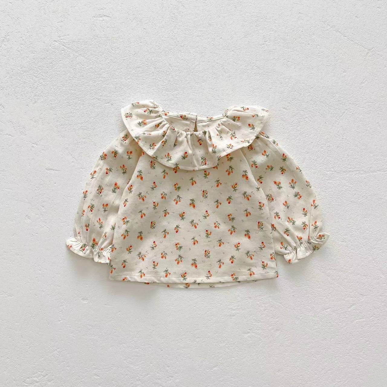 Baby girl wearing a floral pattern ruffle neck shirt combo made of soft corduroy fabric, showcasing apricot and brown colors.