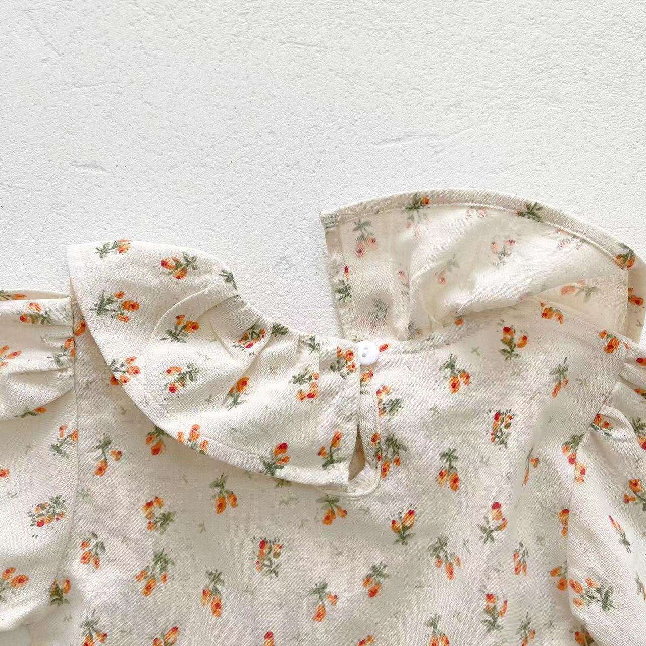 Baby girl wearing a floral pattern ruffle neck shirt combo made of soft corduroy fabric, showcasing apricot and brown colors.