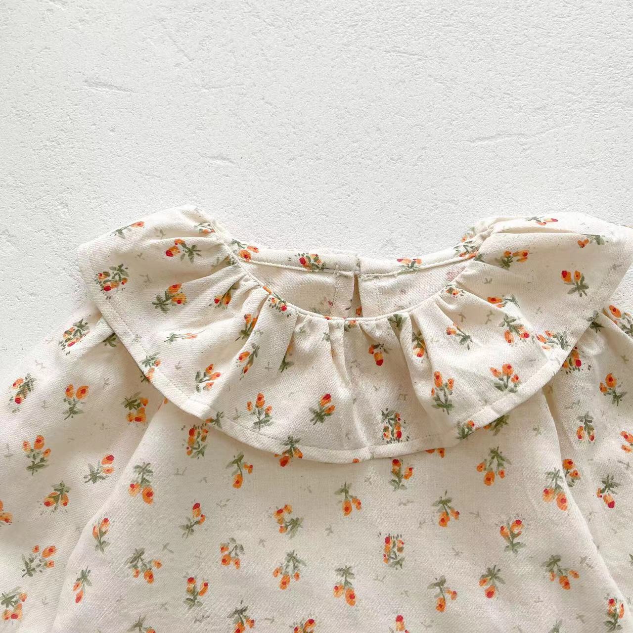 Baby girl wearing a floral pattern ruffle neck shirt combo made of soft corduroy fabric, showcasing apricot and brown colors.