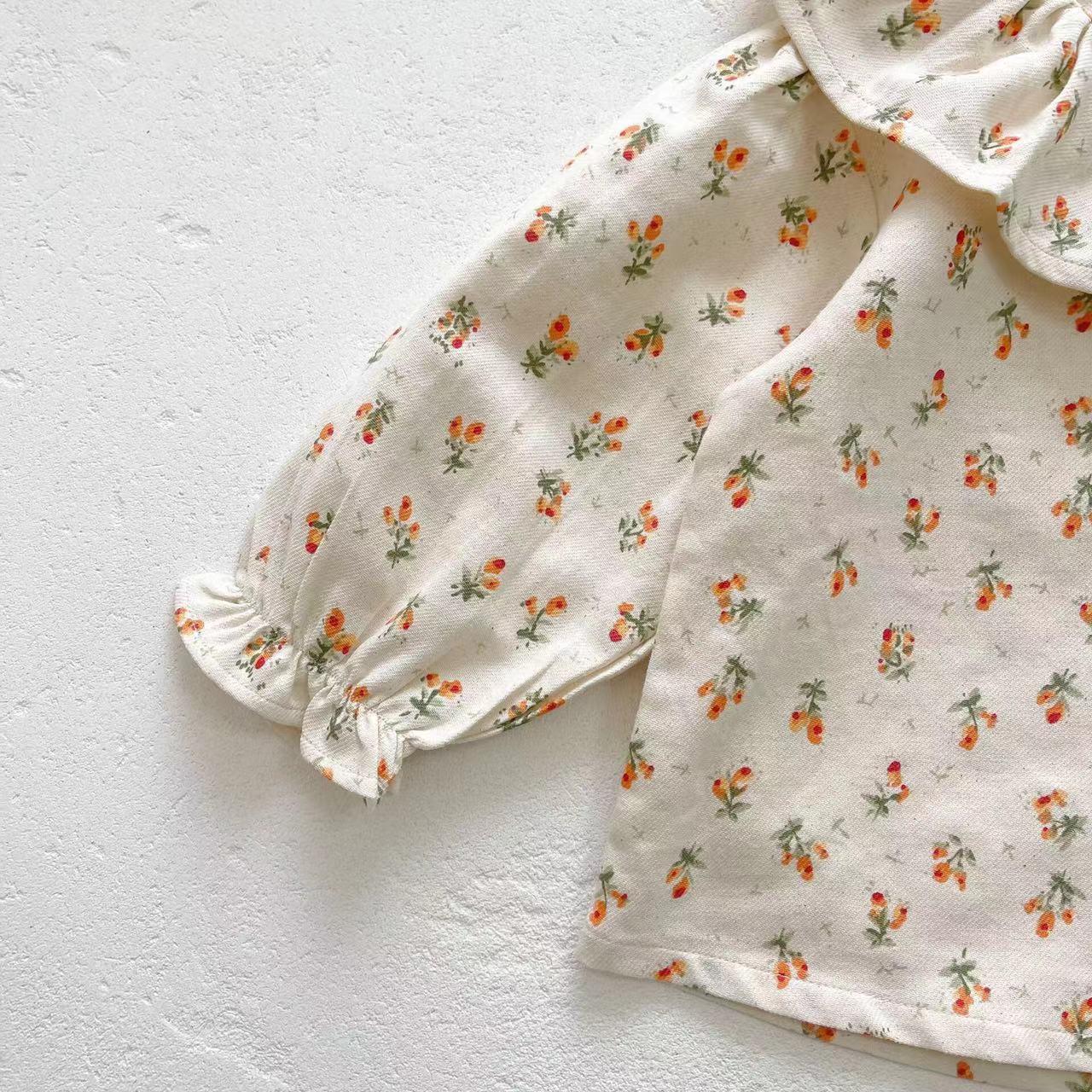 Baby girl wearing a floral pattern ruffle neck shirt combo made of soft corduroy fabric, showcasing apricot and brown colors.