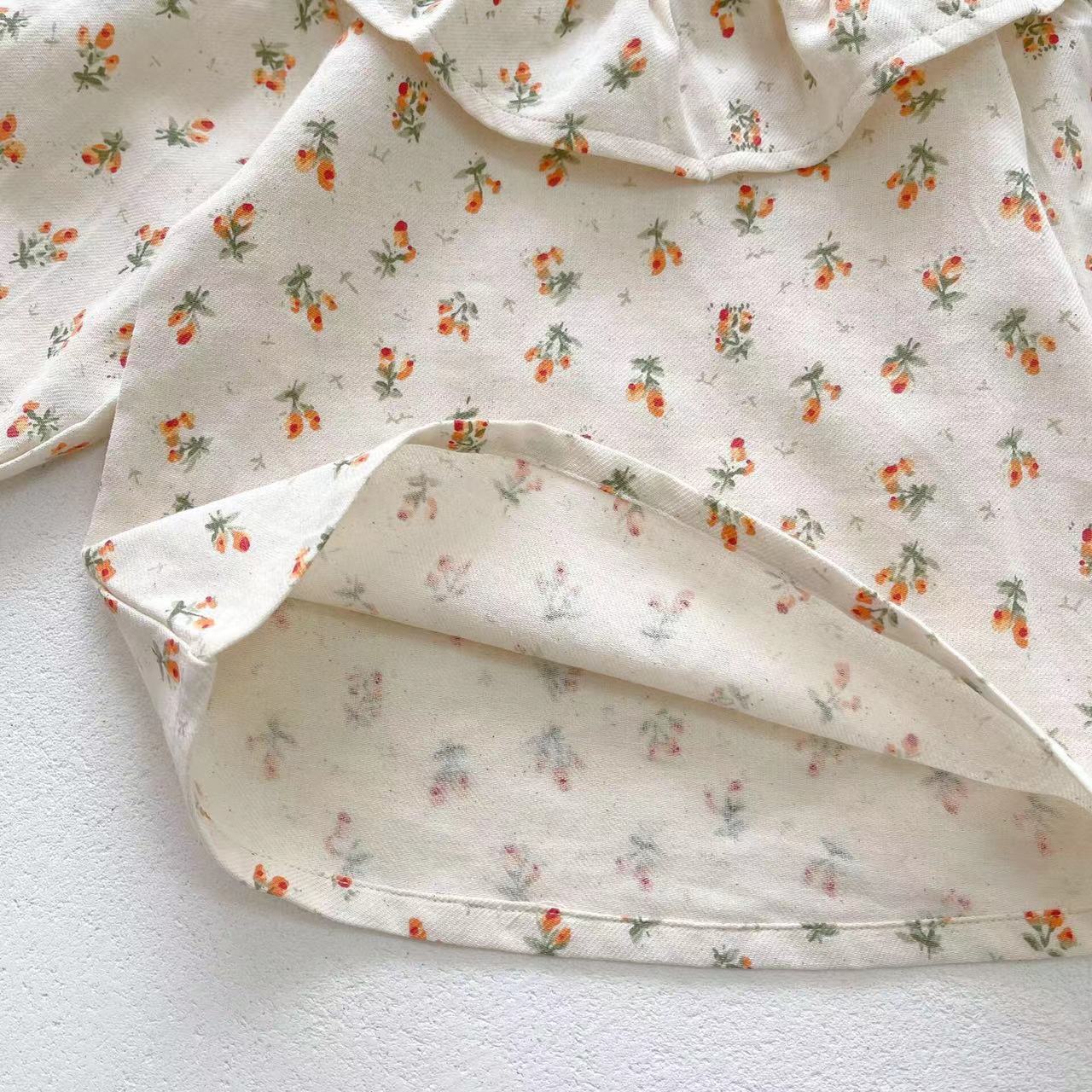 Baby girl wearing a floral pattern ruffle neck shirt combo made of soft corduroy fabric, showcasing apricot and brown colors.