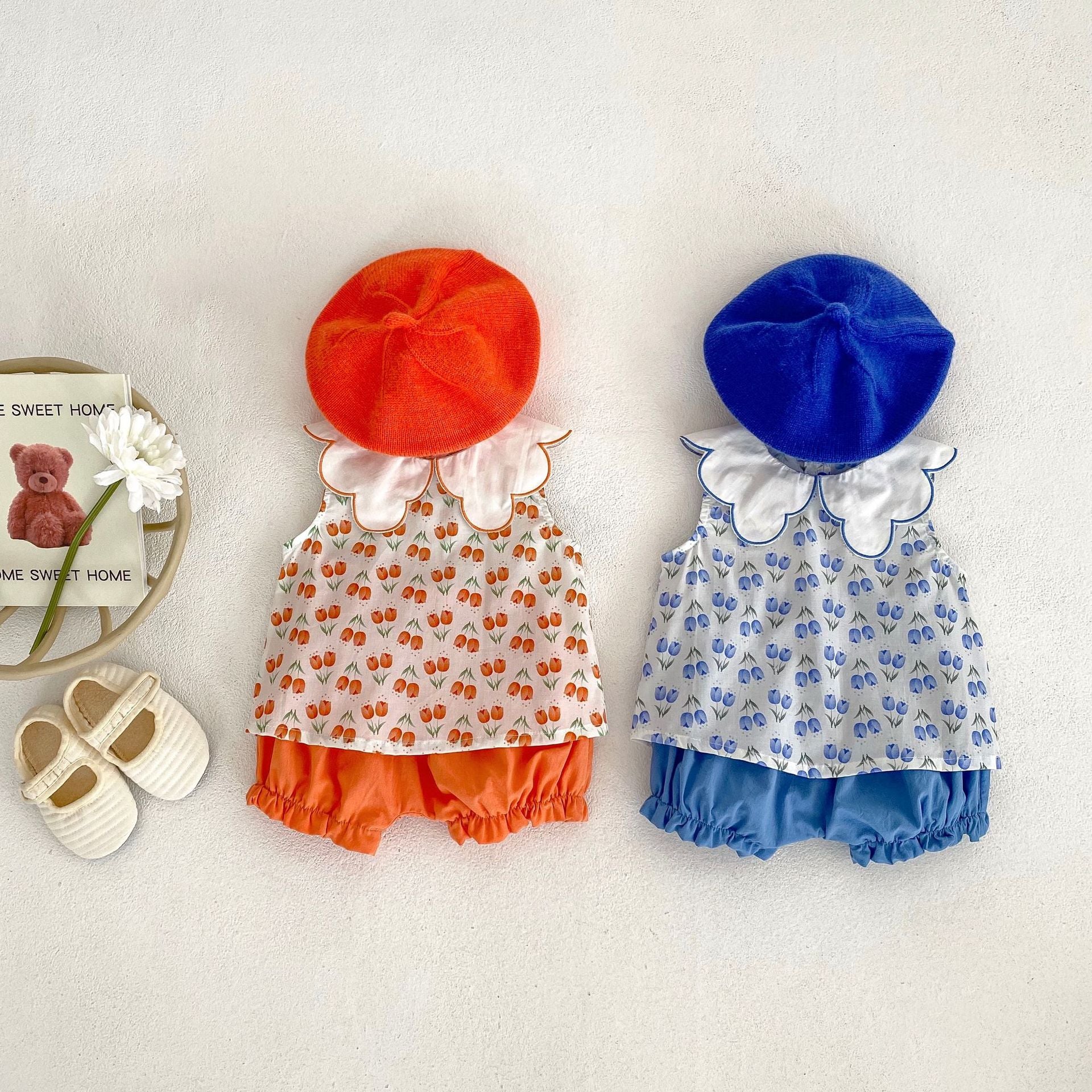 Baby girl wearing a floral pattern ruffle neck shirt and shorts set in blue and orange, perfect for summer.