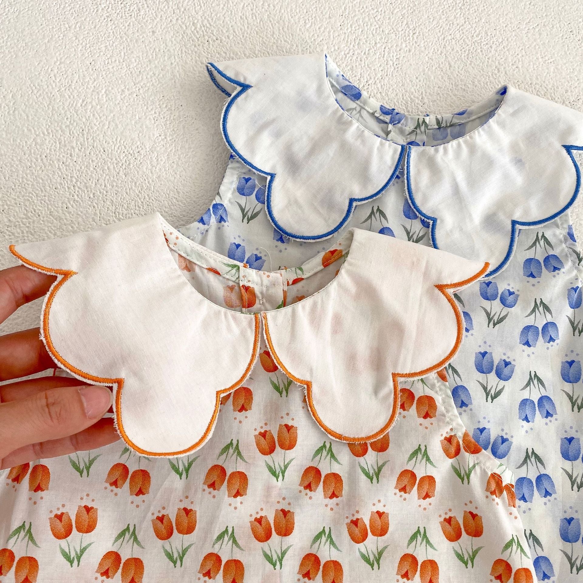 Baby girl wearing a floral pattern ruffle neck shirt and shorts set in blue and orange, perfect for summer.