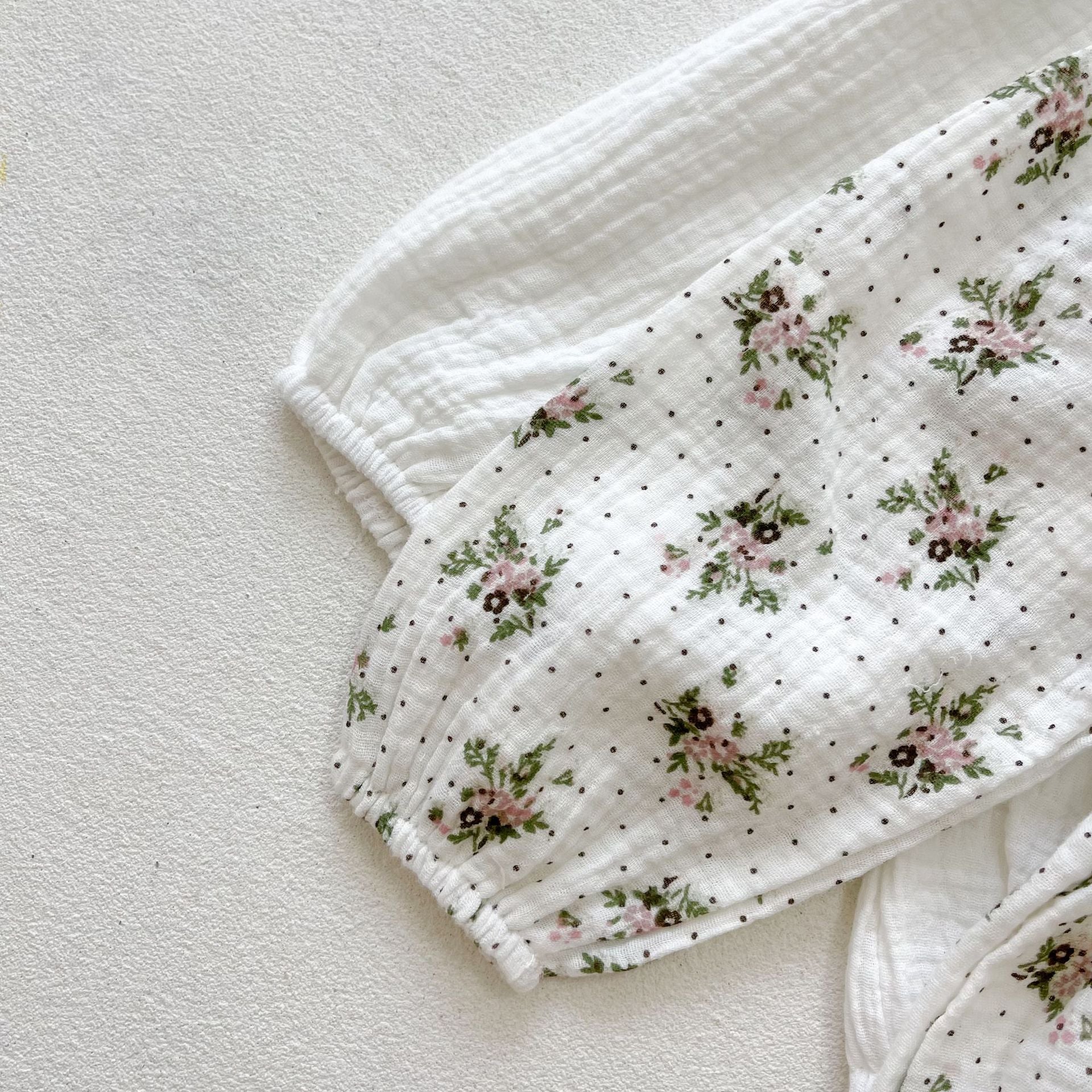 Baby girl wearing a floral print doll collar long-sleeve onesie in white and pink, showcasing a stylish design.