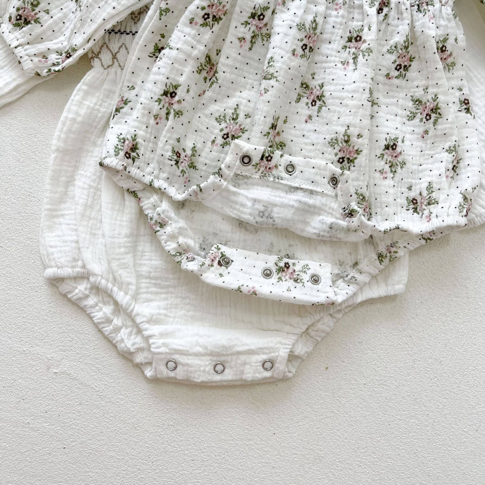 Baby girl wearing a floral print doll collar long-sleeve onesie in white and pink, showcasing a stylish design.