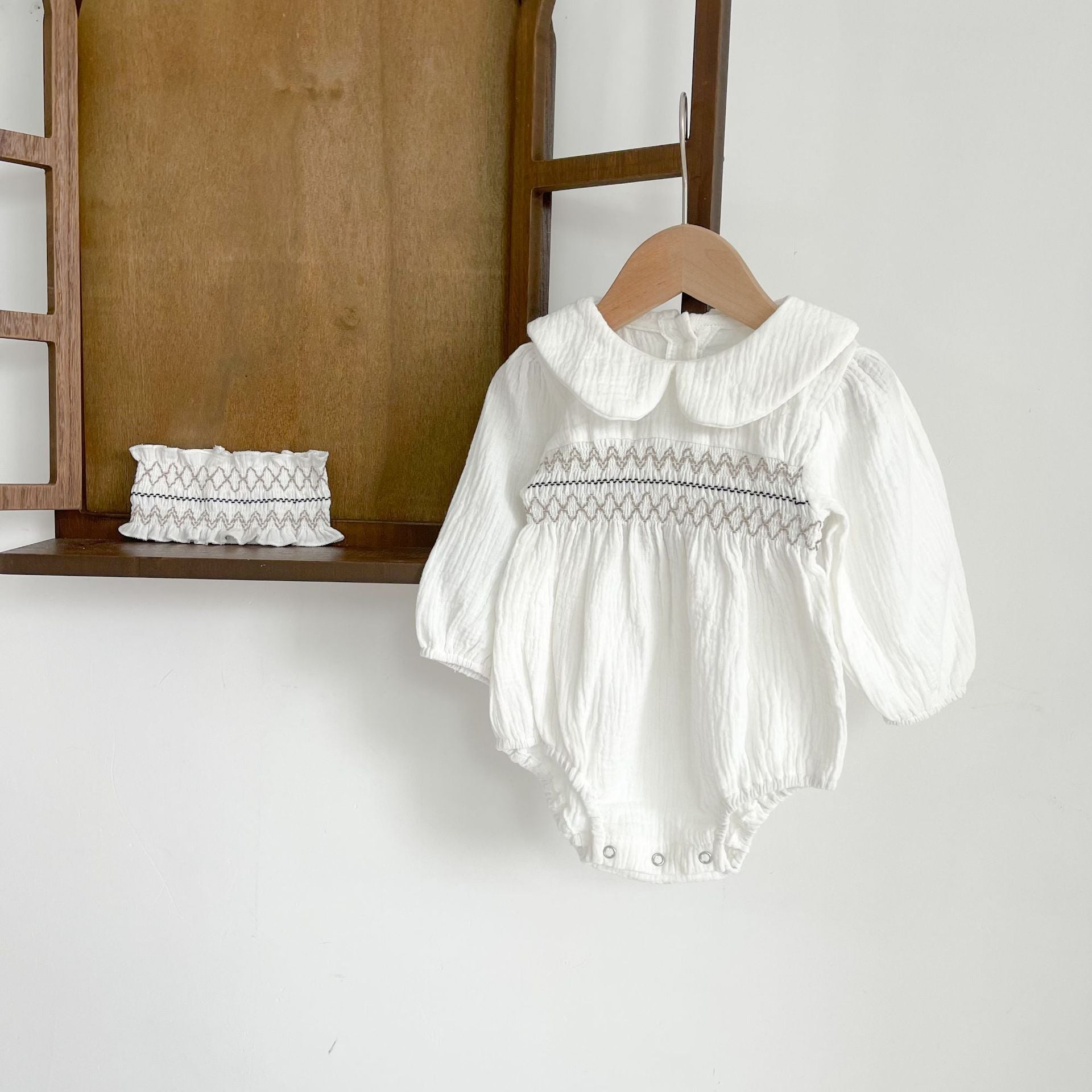 Baby girl wearing a floral print doll collar long-sleeve onesie in white and pink, showcasing a stylish design.