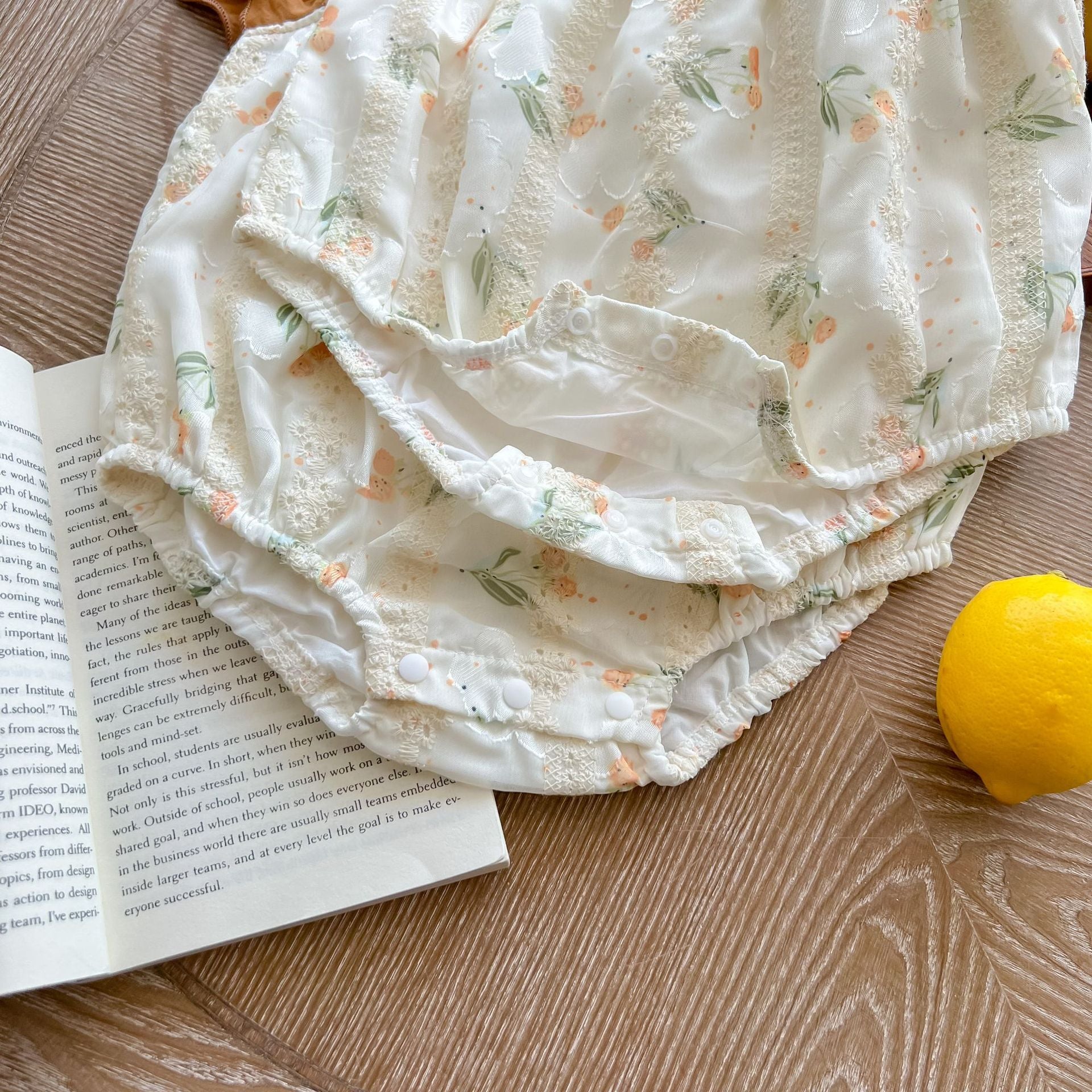 Baby girl floral print onesie with embroidered design and ruffle sleeves in green and brown colors.