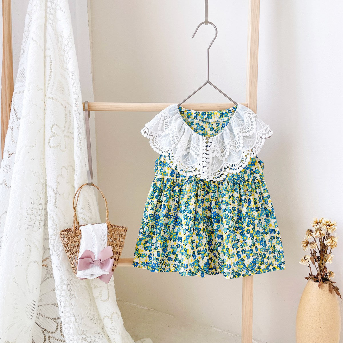 A beautiful baby girl wearing a floral print lace patchwork dress with an O-neck design, showcasing vibrant green colors and intricate patterns.