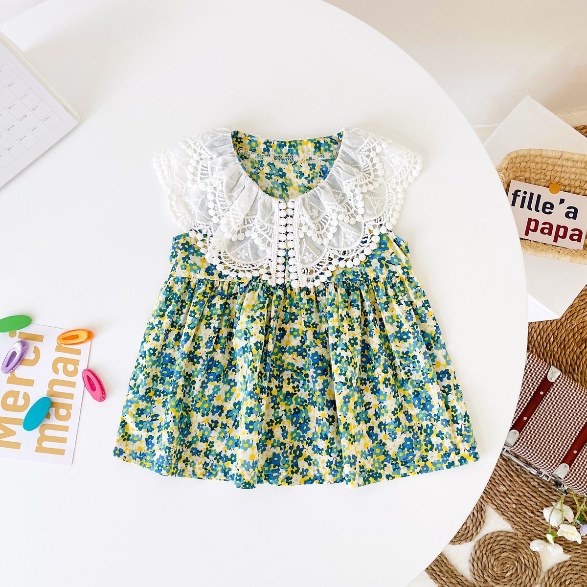 A beautiful baby girl wearing a floral print lace patchwork dress with an O-neck design, showcasing vibrant green colors and intricate patterns.