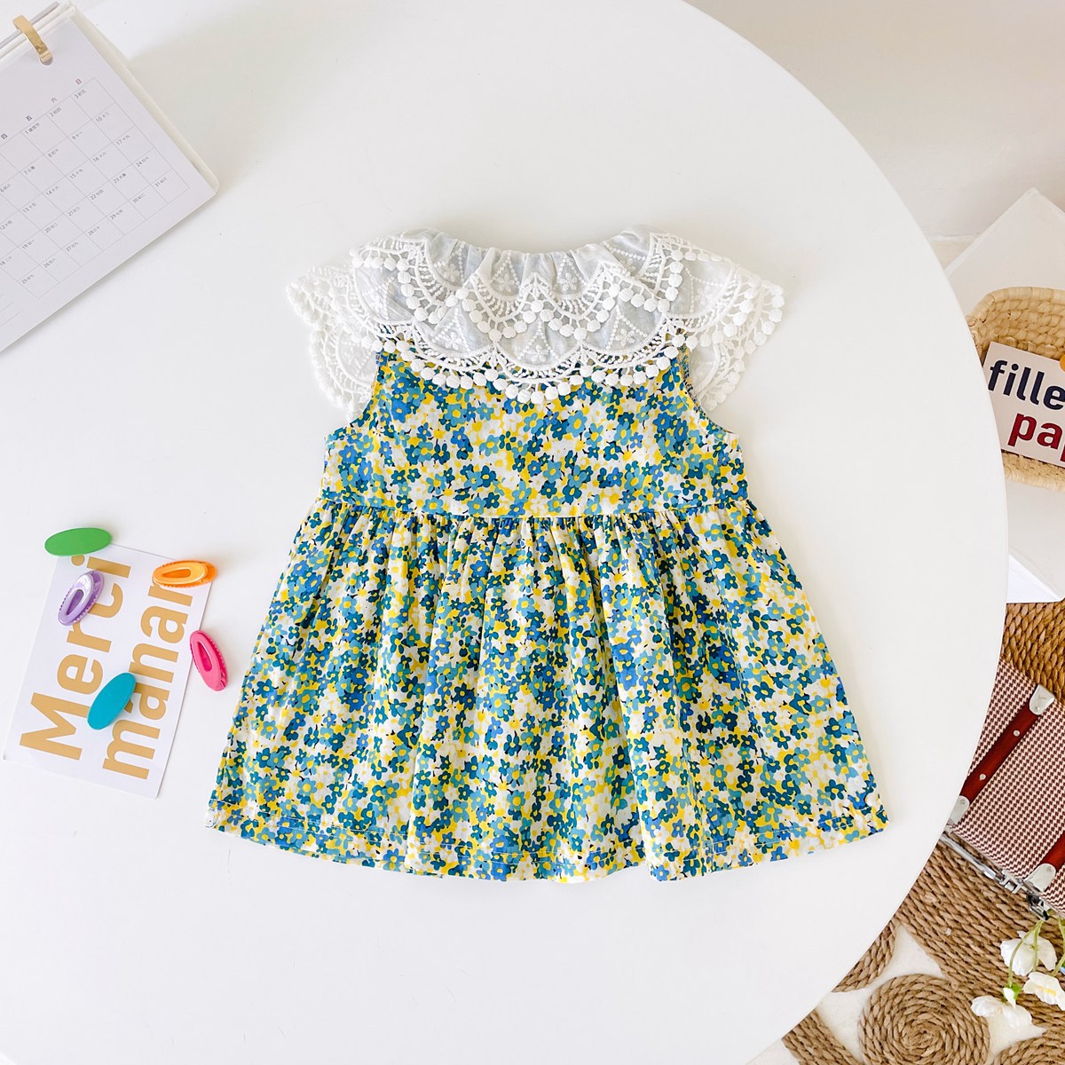 A beautiful baby girl wearing a floral print lace patchwork dress with an O-neck design, showcasing vibrant green colors and intricate patterns.