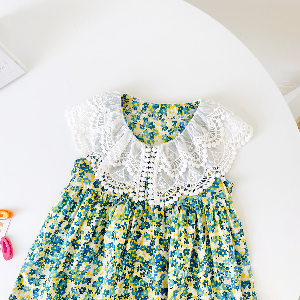 A beautiful baby girl wearing a floral print lace patchwork dress with an O-neck design, showcasing vibrant green colors and intricate patterns.