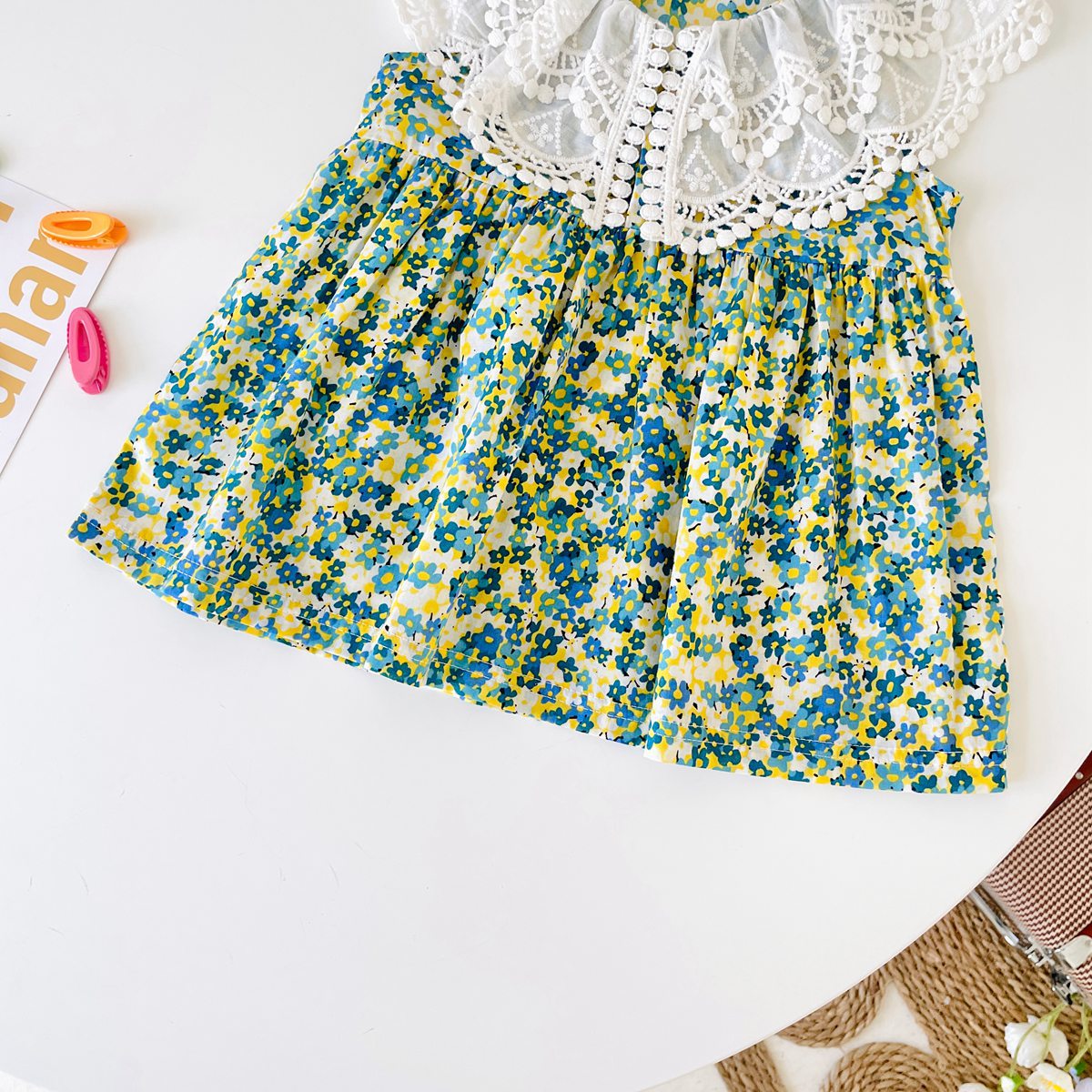 A beautiful baby girl wearing a floral print lace patchwork dress with an O-neck design, showcasing vibrant green colors and intricate patterns.