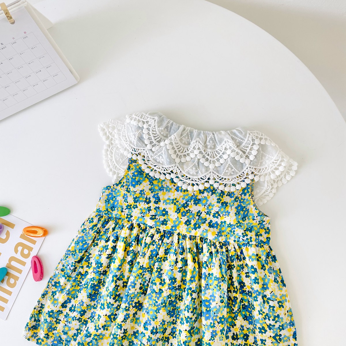 A beautiful baby girl wearing a floral print lace patchwork dress with an O-neck design, showcasing vibrant green colors and intricate patterns.