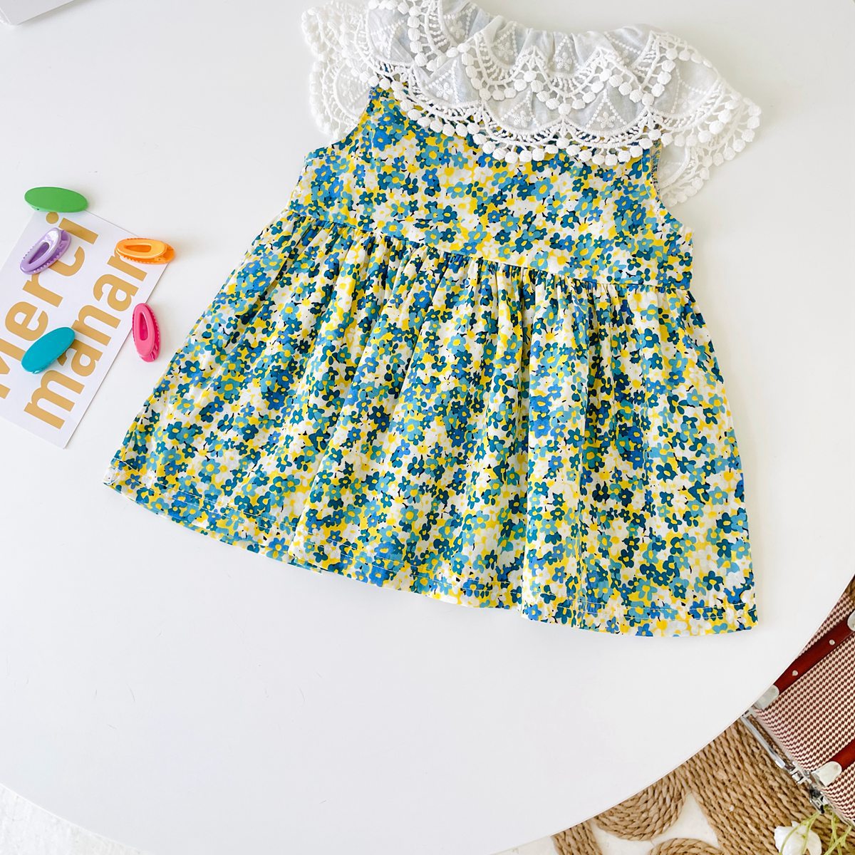 A beautiful baby girl wearing a floral print lace patchwork dress with an O-neck design, showcasing vibrant green colors and intricate patterns.