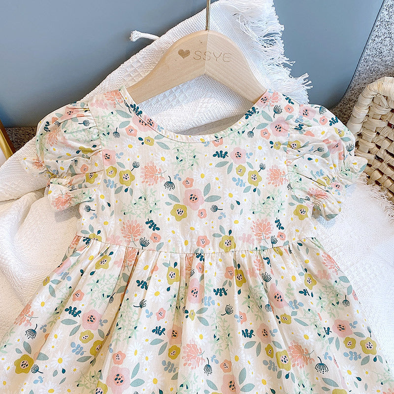 A cute baby girl wearing a floral print O-neck puff-sleeved short dress in apricot color, perfect for summer occasions.