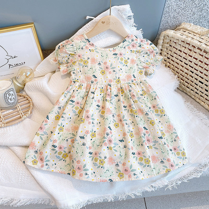 A cute baby girl wearing a floral print O-neck puff-sleeved short dress in apricot color, perfect for summer occasions.