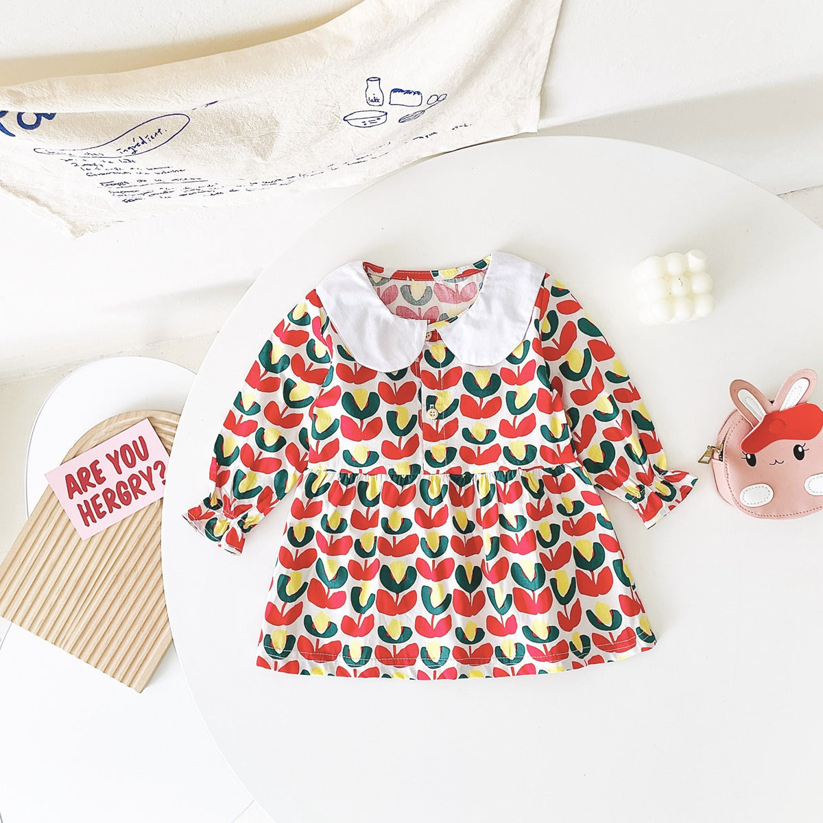 A beautiful baby girl dress featuring a floral print pattern with a doll neck and A-line design, available in red and green colors.