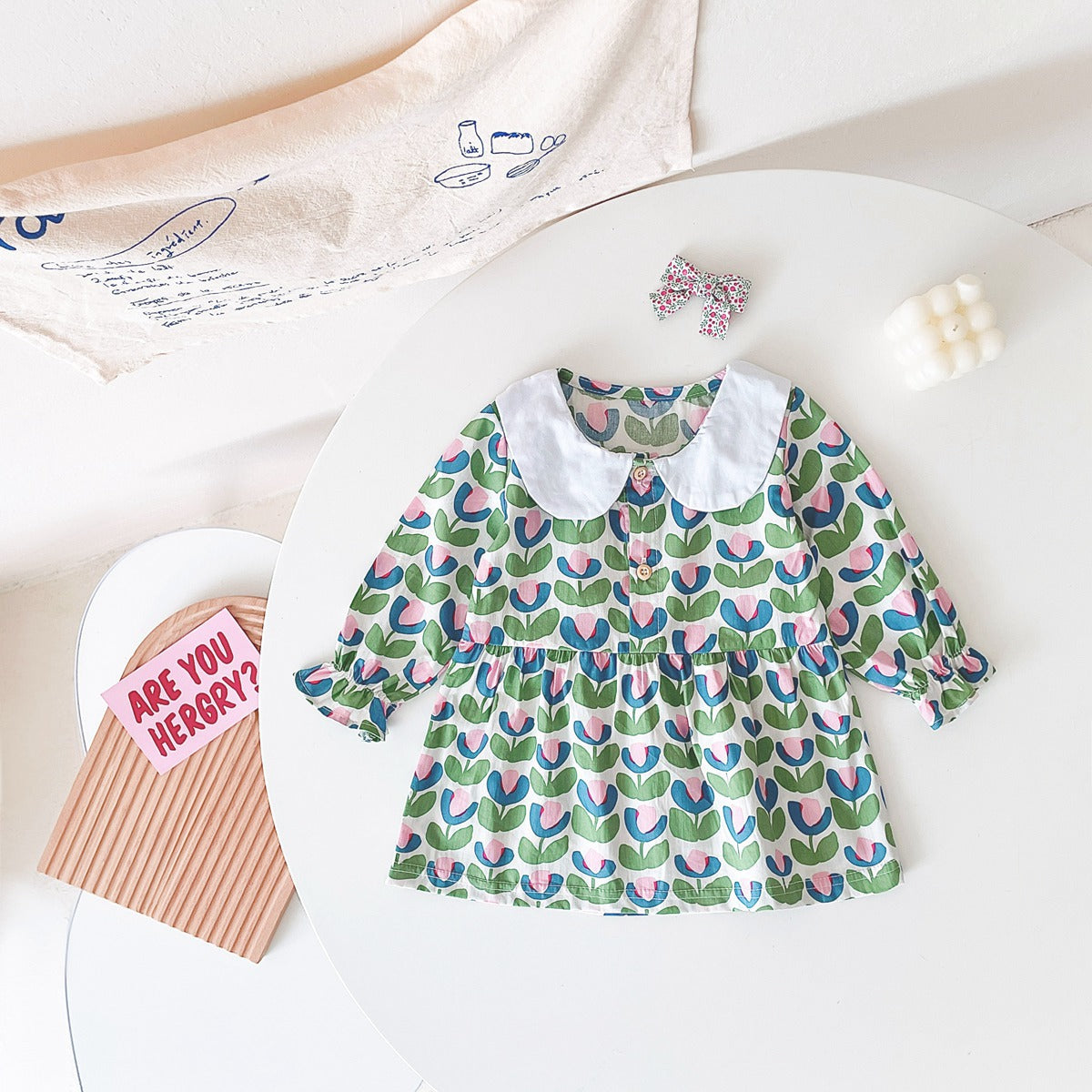 A beautiful baby girl dress featuring a floral print pattern with a doll neck and A-line design, available in red and green colors.