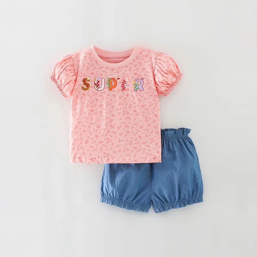 Baby girl wearing a floral and slogan print puff sleeve tee with denim shorts, showcasing a trendy summer outfit.