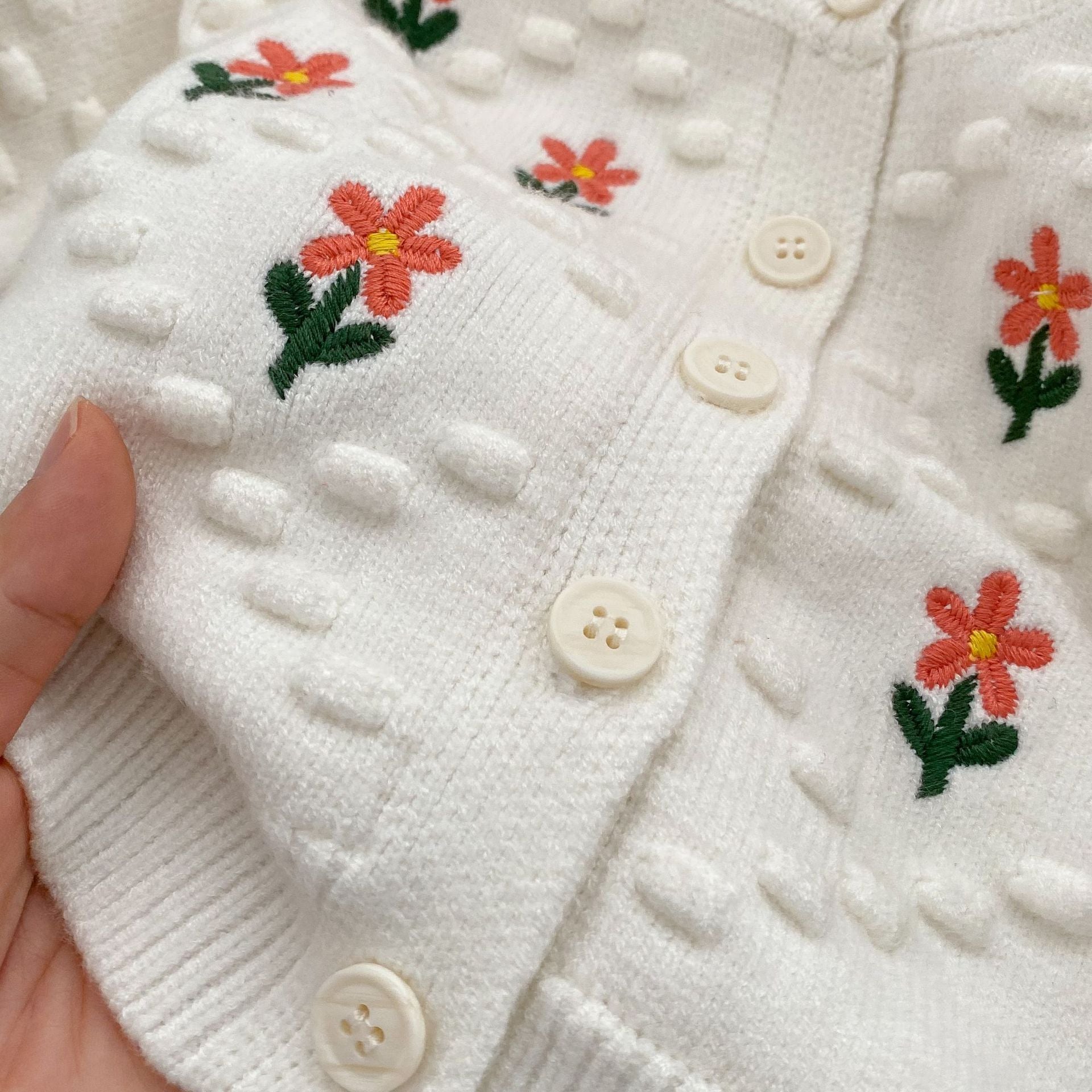 A cozy baby girl cardigan featuring flower embroidery, thickened knit design, available in white and red colors.