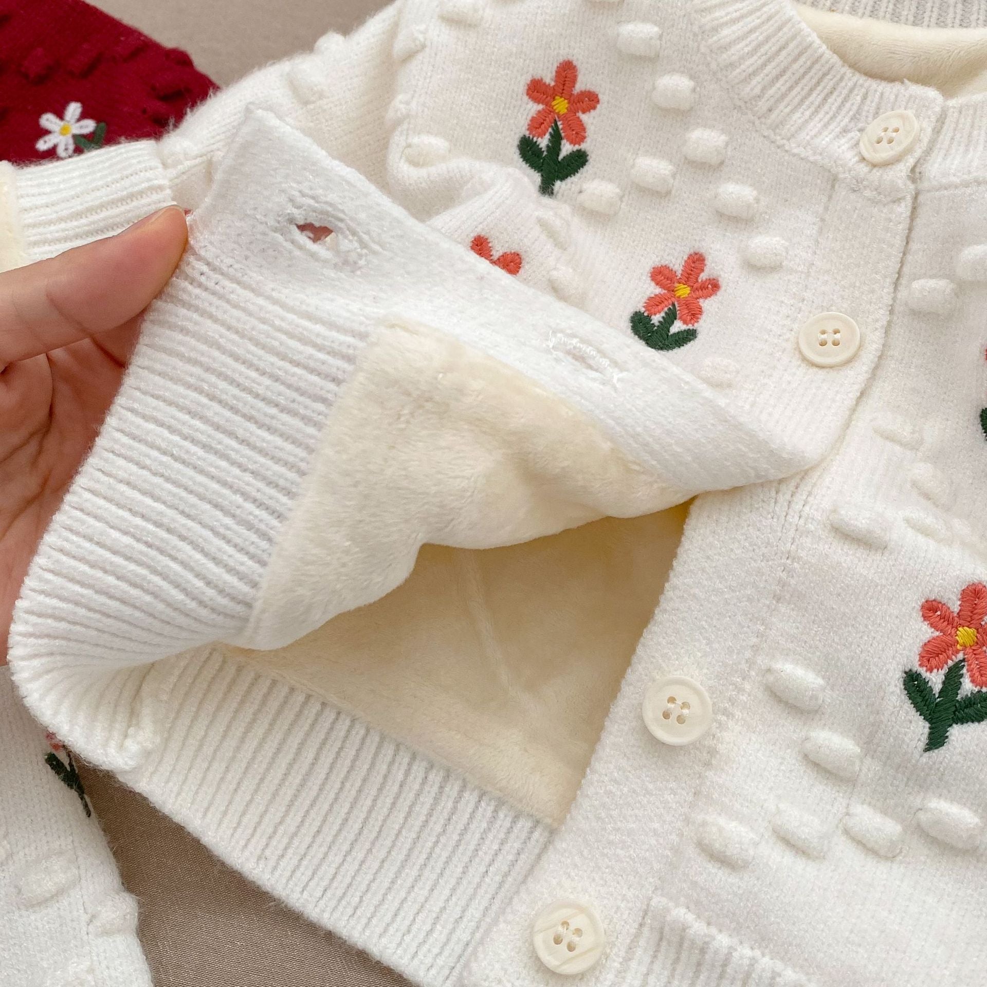 A cozy baby girl cardigan featuring flower embroidery, thickened knit design, available in white and red colors.