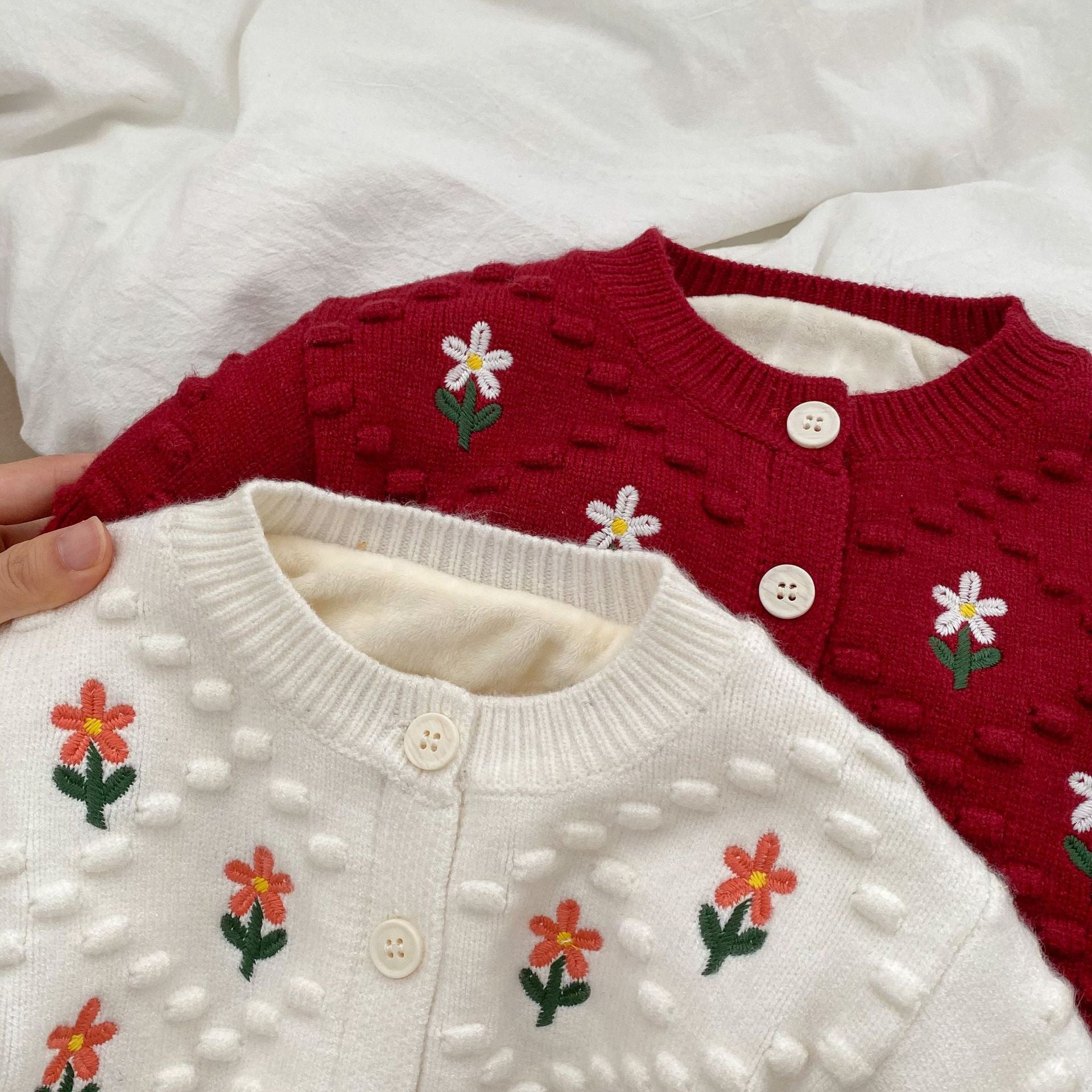 A cozy baby girl cardigan featuring flower embroidery, thickened knit design, available in white and red colors.