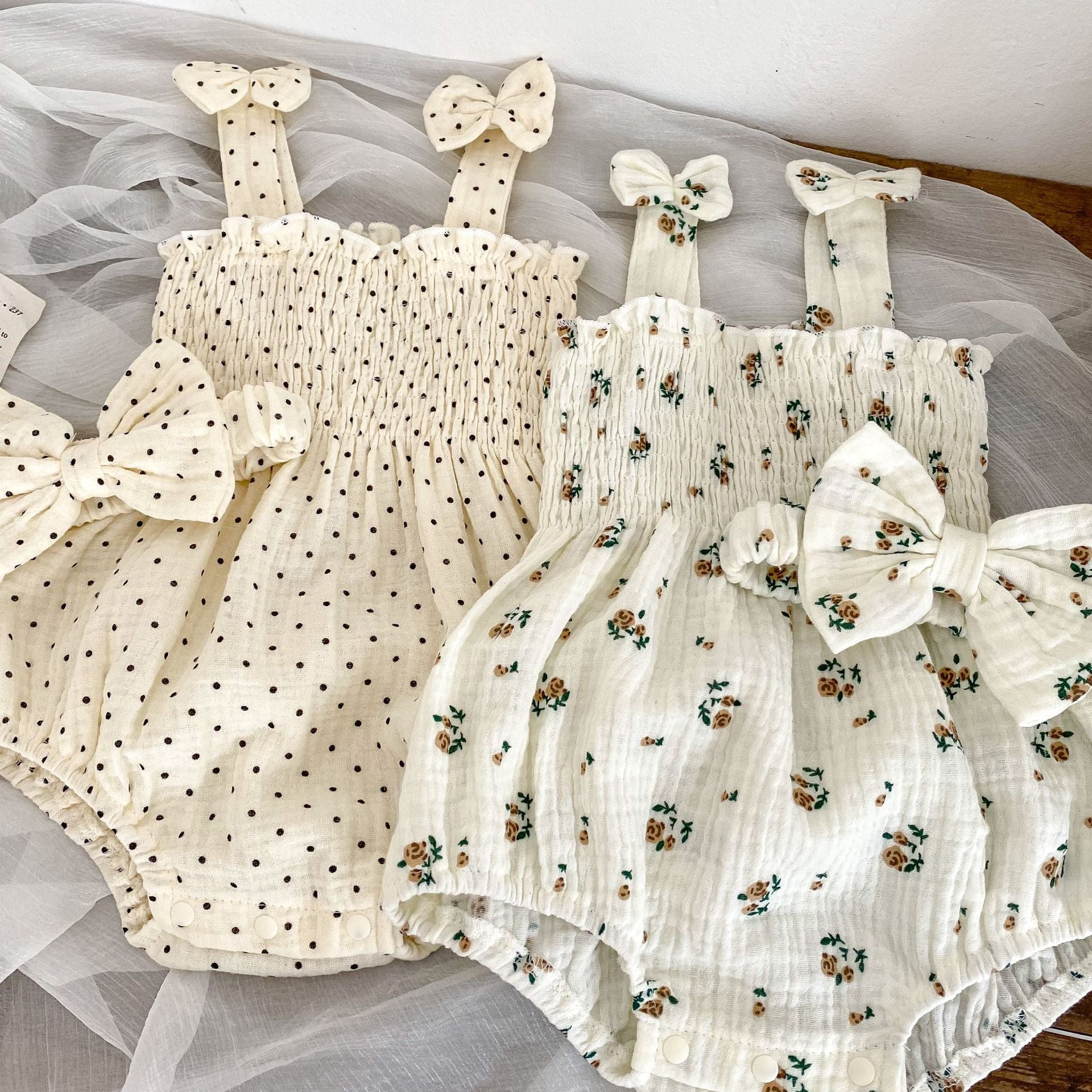 Baby girl wearing a floral pattern sling onesie in white and apricot colors, perfect for summer outings.