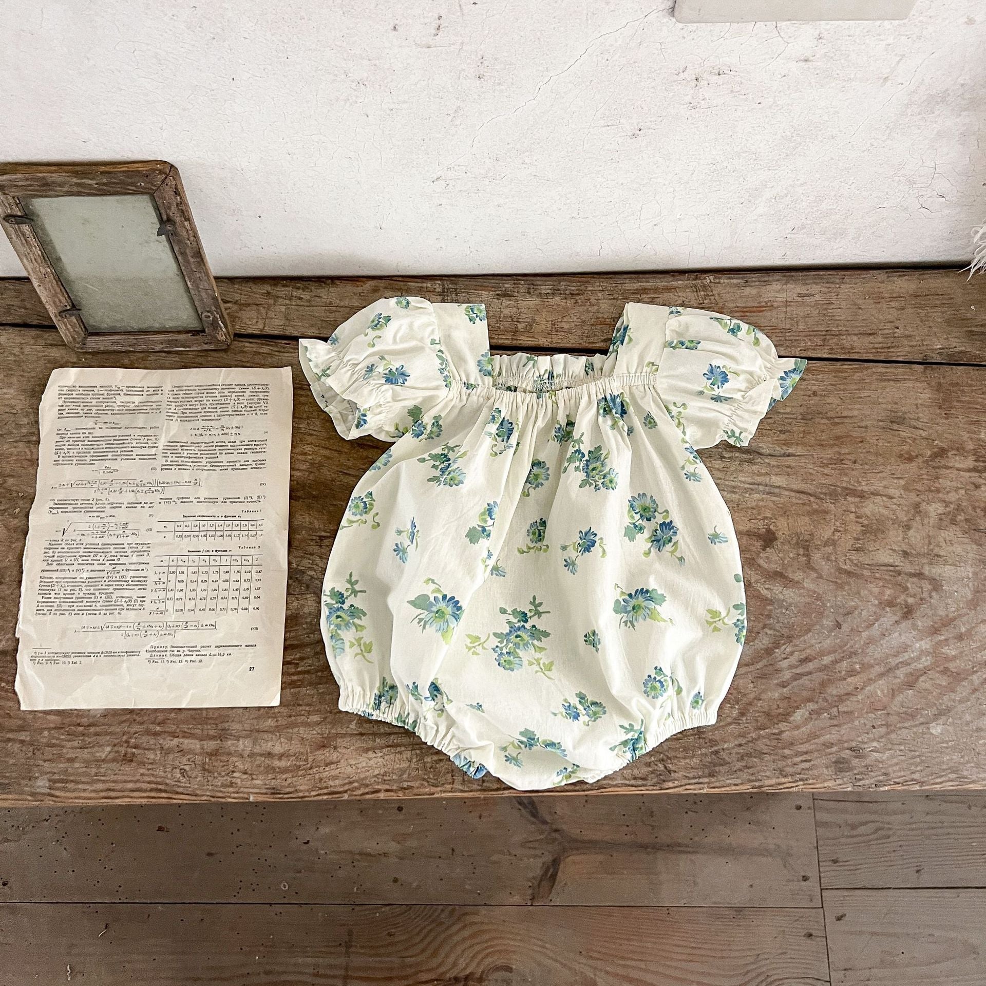 Baby girl wearing a floral pattern square neck onesie in green and apricot colors, showcasing a stylish summer outfit.