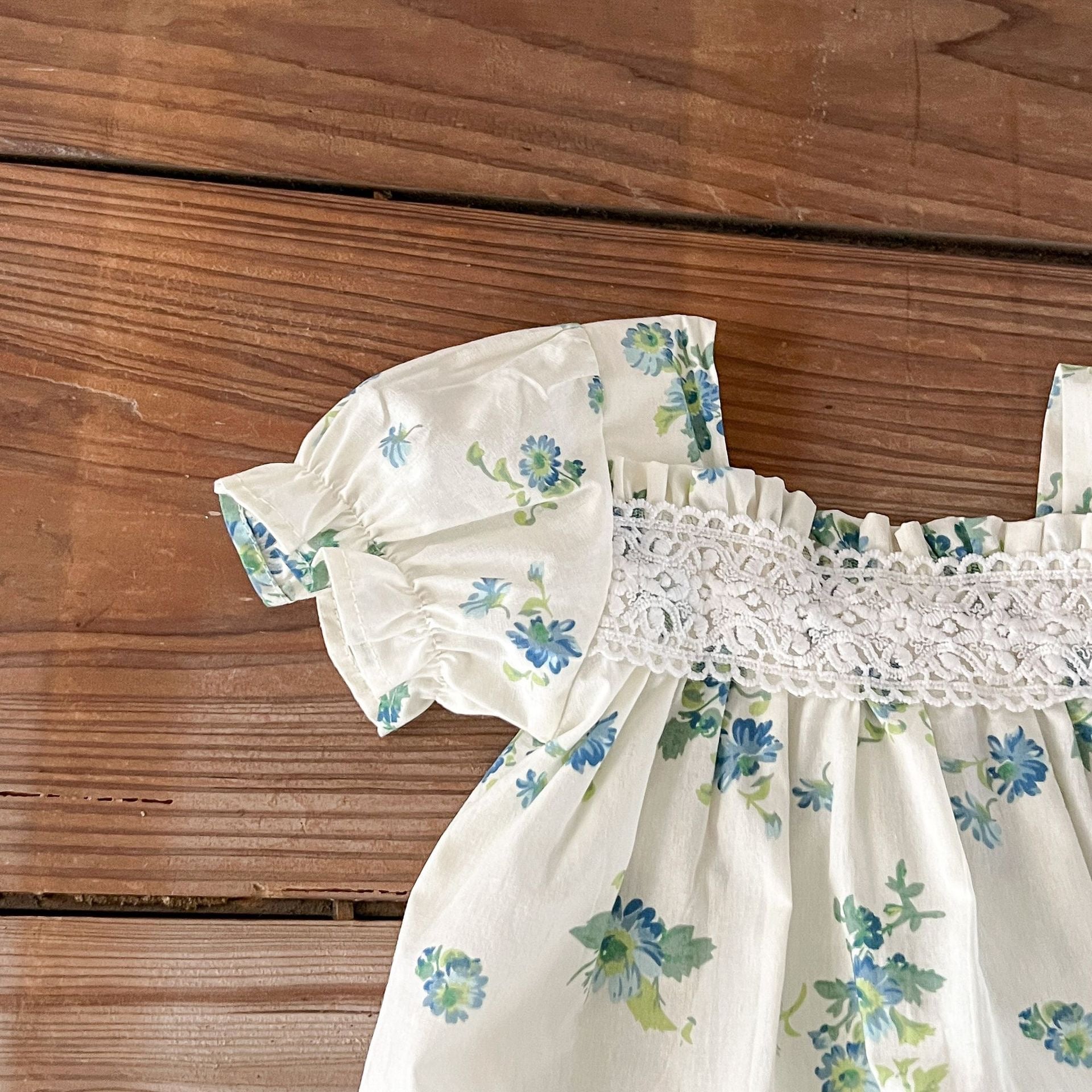 Baby girl wearing a floral pattern square neck onesie in green and apricot colors, showcasing a stylish summer outfit.