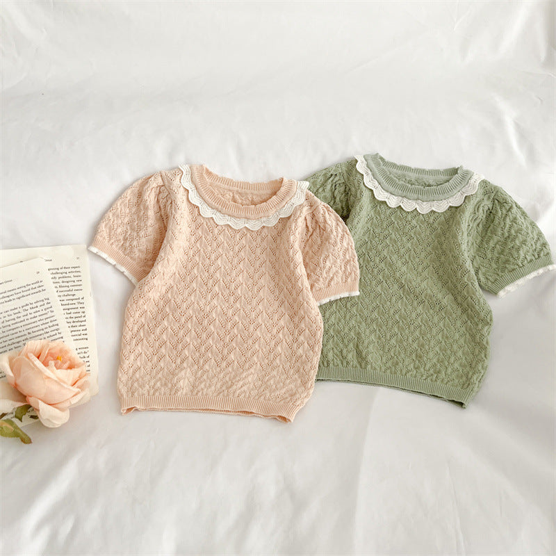 A cute baby girl wearing a hollow carved design ruffle knit tee in pink, showcasing its charming details and soft cotton material.