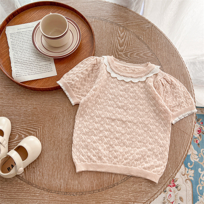 A cute baby girl wearing a hollow carved design ruffle knit tee in pink, showcasing its charming details and soft cotton material.