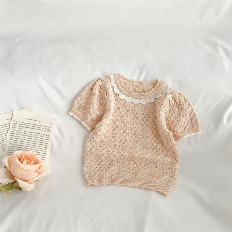 A cute baby girl wearing a hollow carved design ruffle knit tee in pink, showcasing its charming details and soft cotton material.