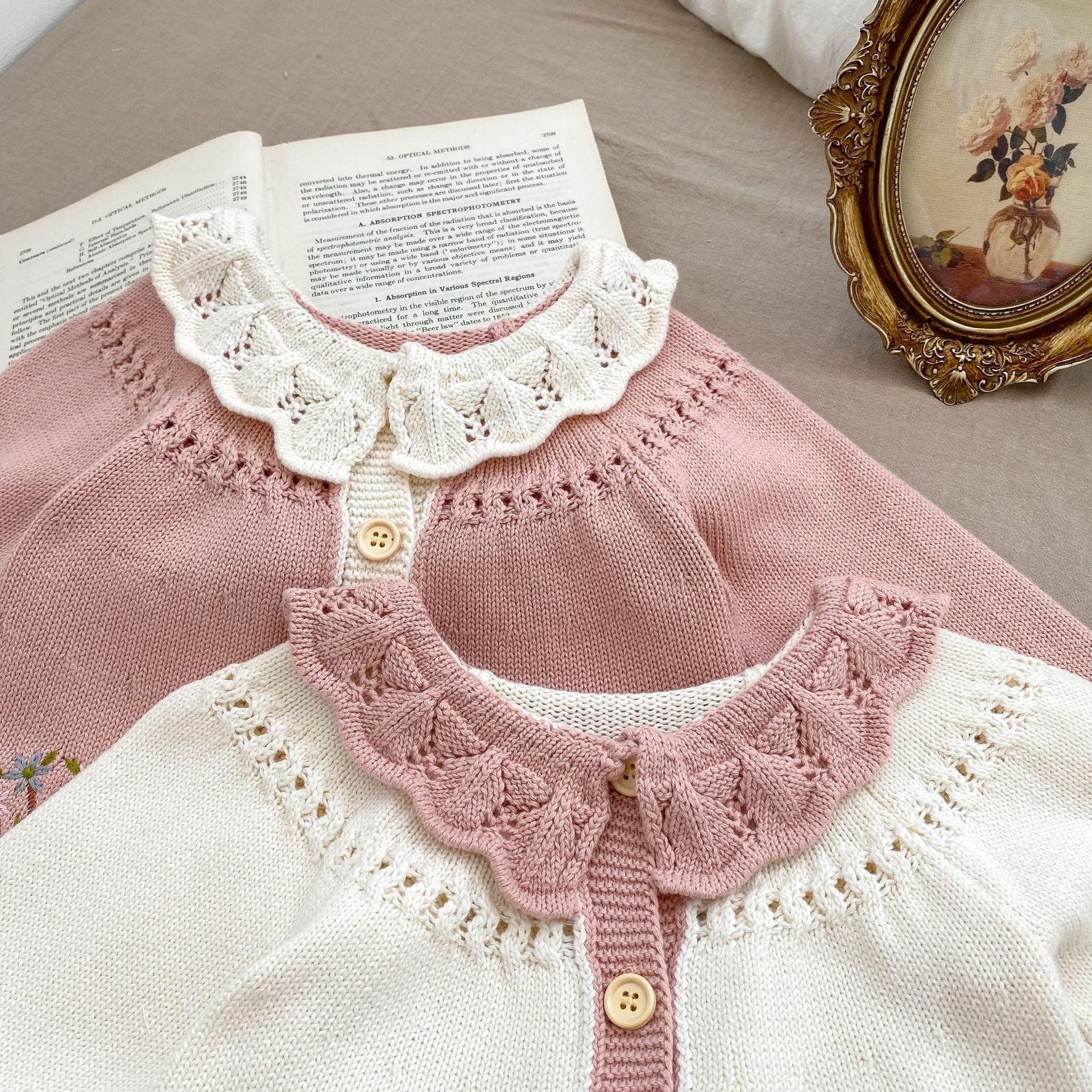 A baby girl wearing a pink embroidered long-sleeved cardigan, showcasing its soft cotton fabric and stylish design.