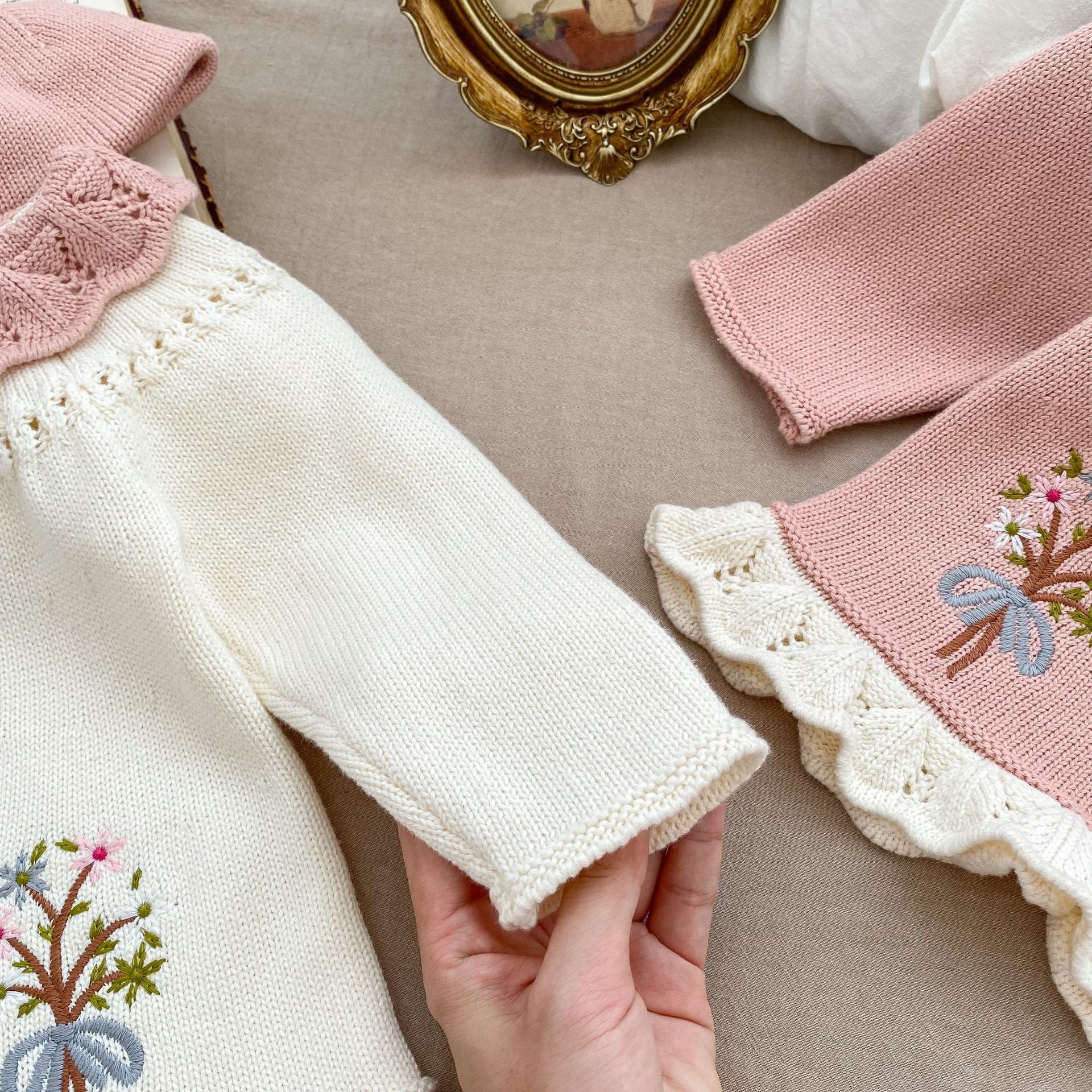 A baby girl wearing a pink embroidered long-sleeved cardigan, showcasing its soft cotton fabric and stylish design.