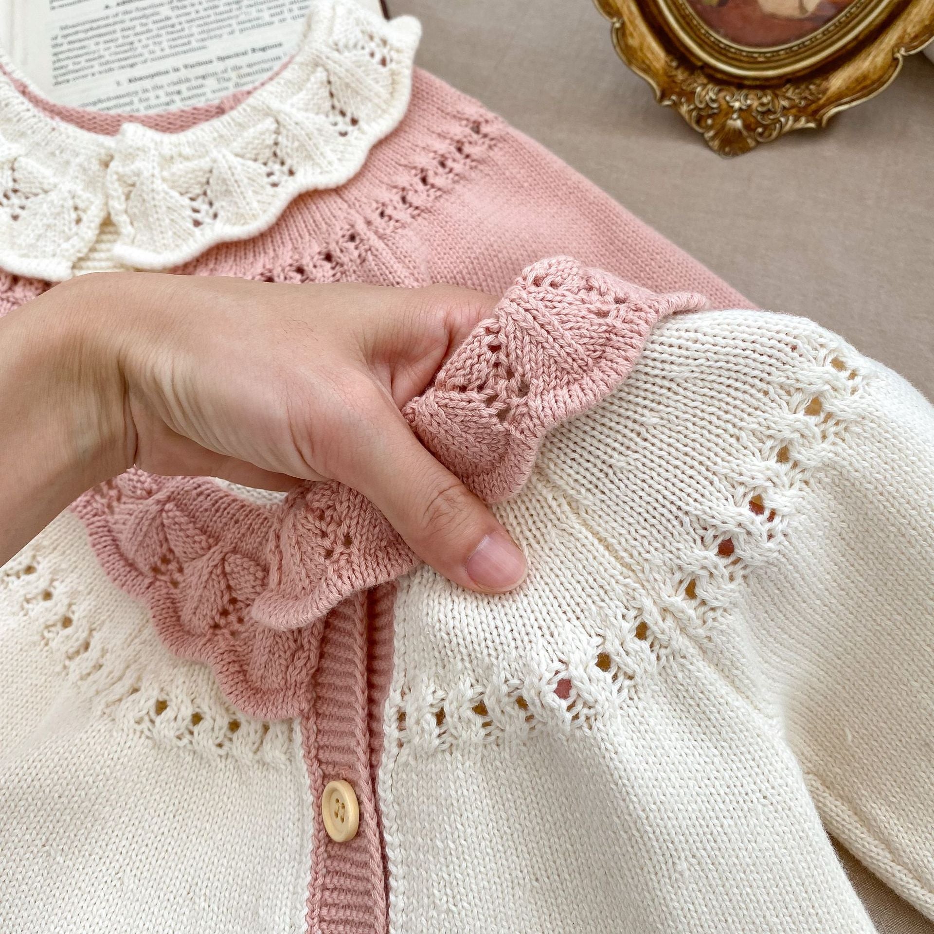 A baby girl wearing a pink embroidered long-sleeved cardigan, showcasing its soft cotton fabric and stylish design.