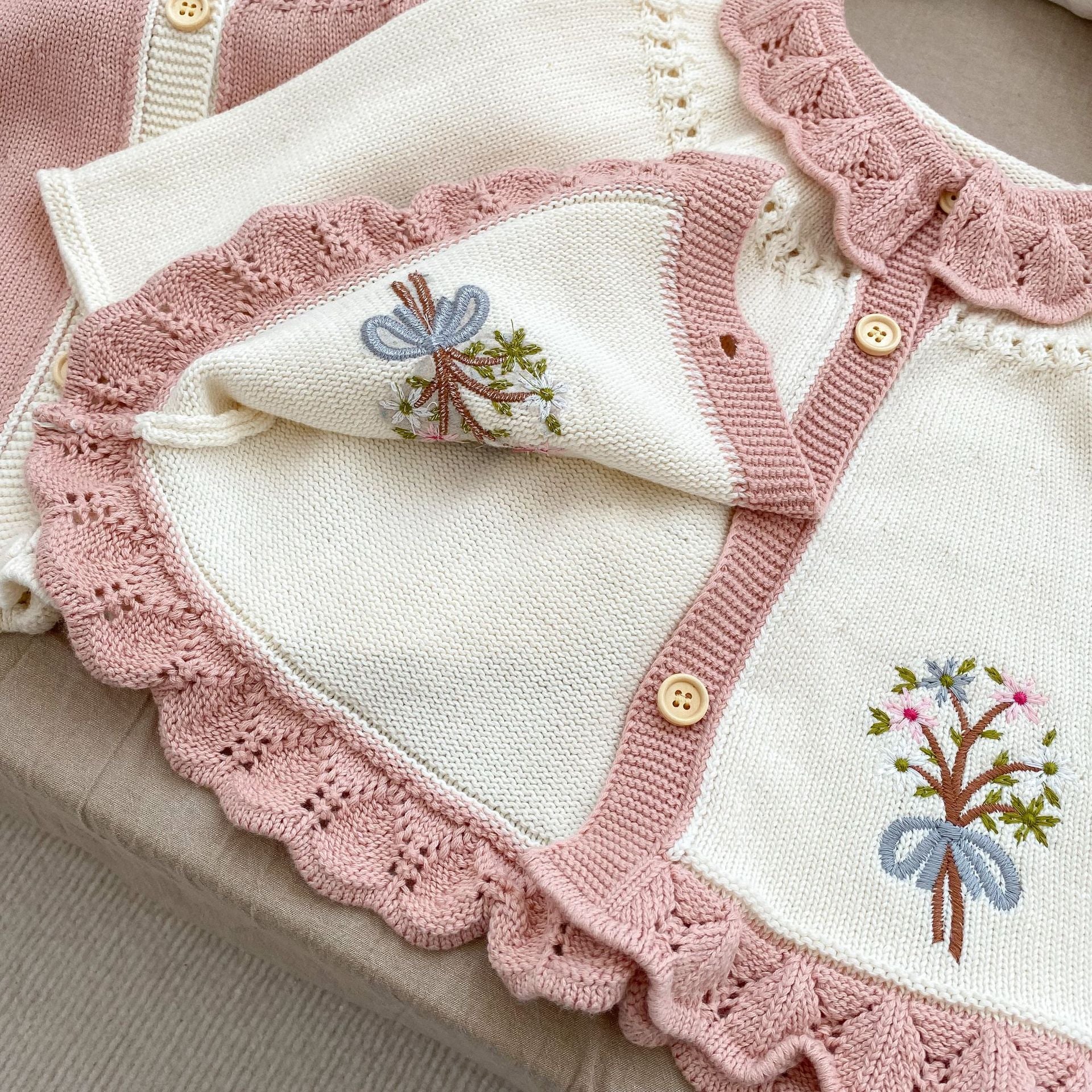 A baby girl wearing a pink embroidered long-sleeved cardigan, showcasing its soft cotton fabric and stylish design.