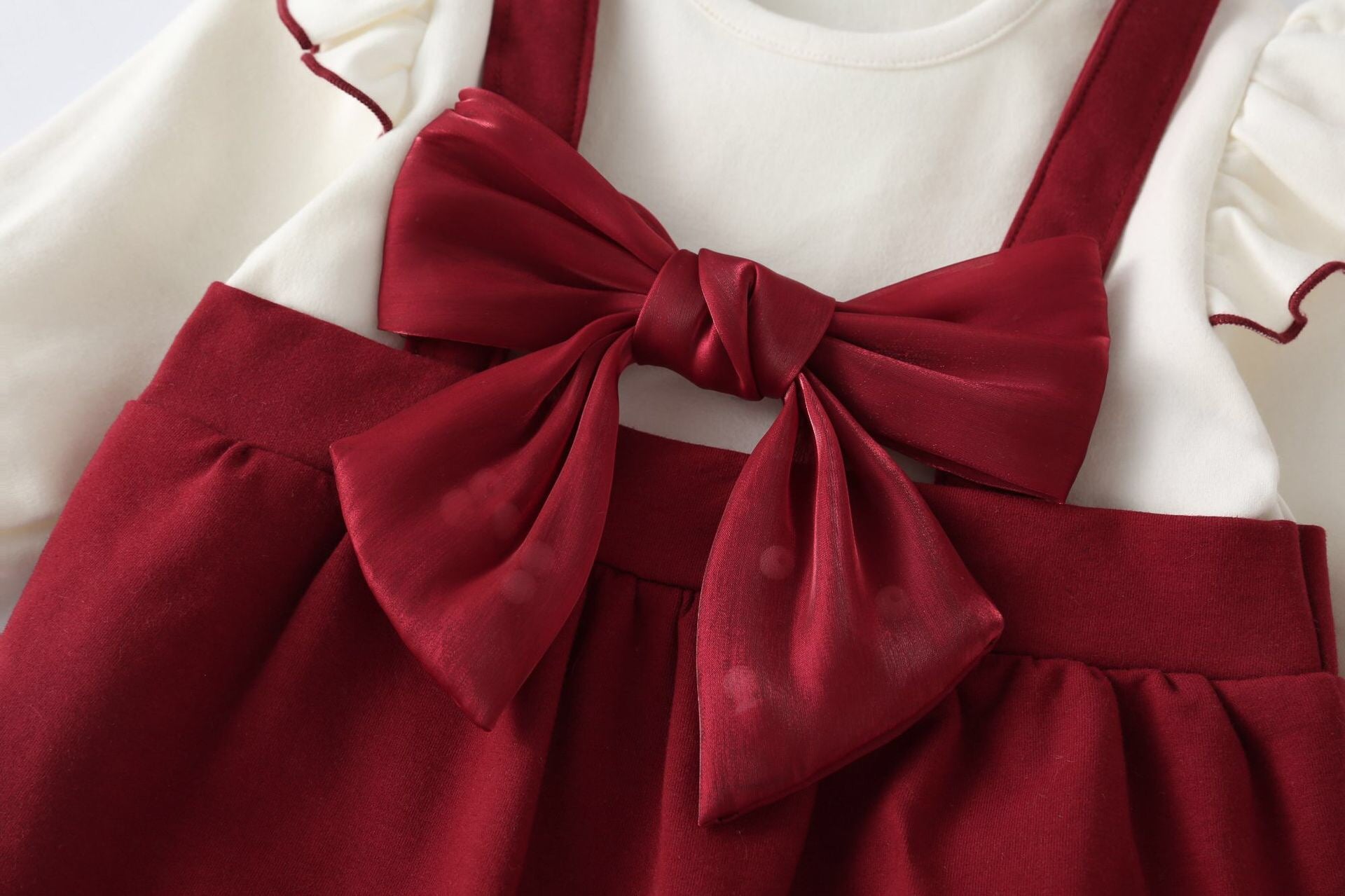 A stylish Baby Girl Lettuce Trim Design Big Bow Long Sleeve Jumpsuit in vibrant red, featuring a chic big bow and playful lettuce trim.