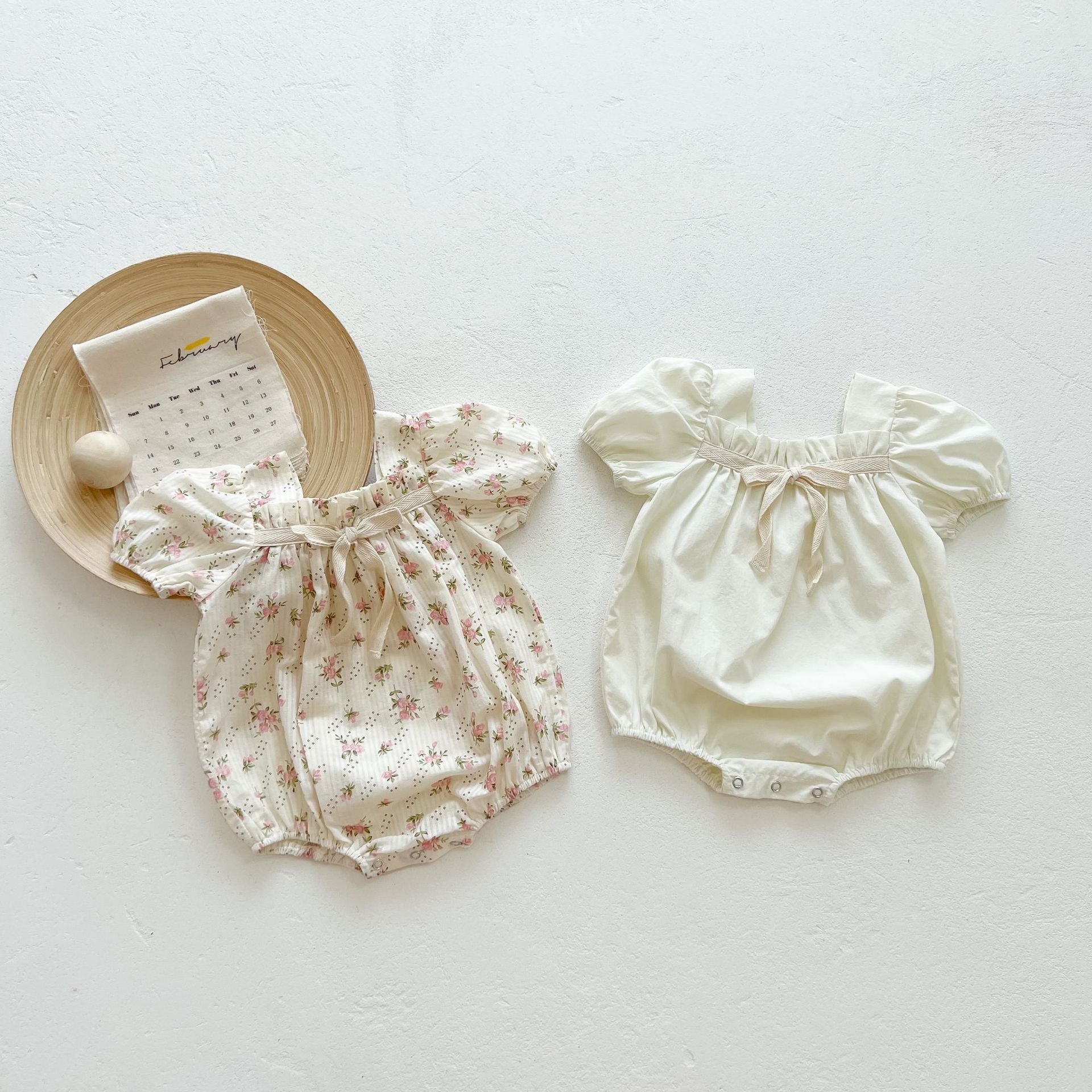 Baby girl onesie featuring a lovely bow-tie design, short sleeves, available in beige and apricot colors.