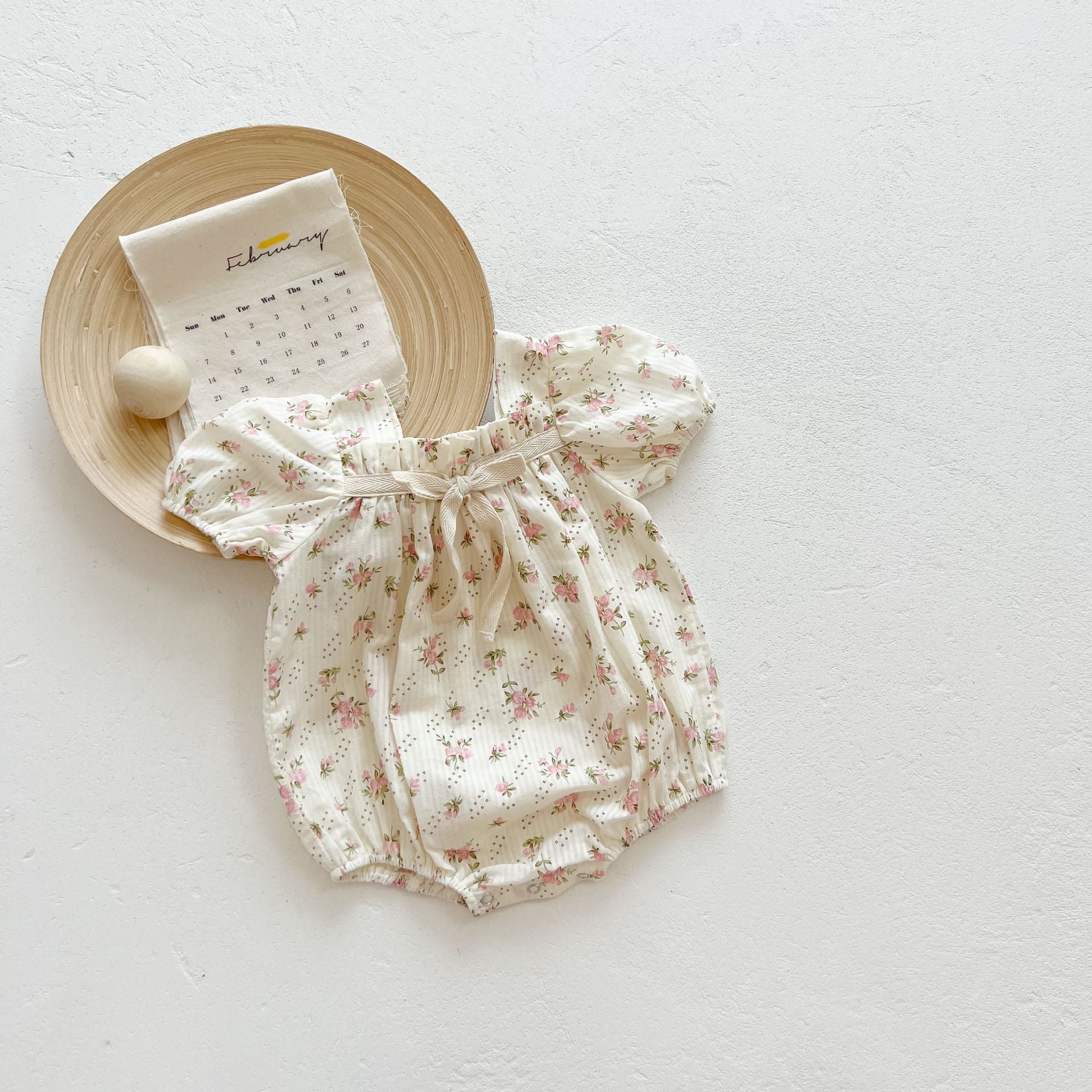 Baby girl onesie featuring a lovely bow-tie design, short sleeves, available in beige and apricot colors.