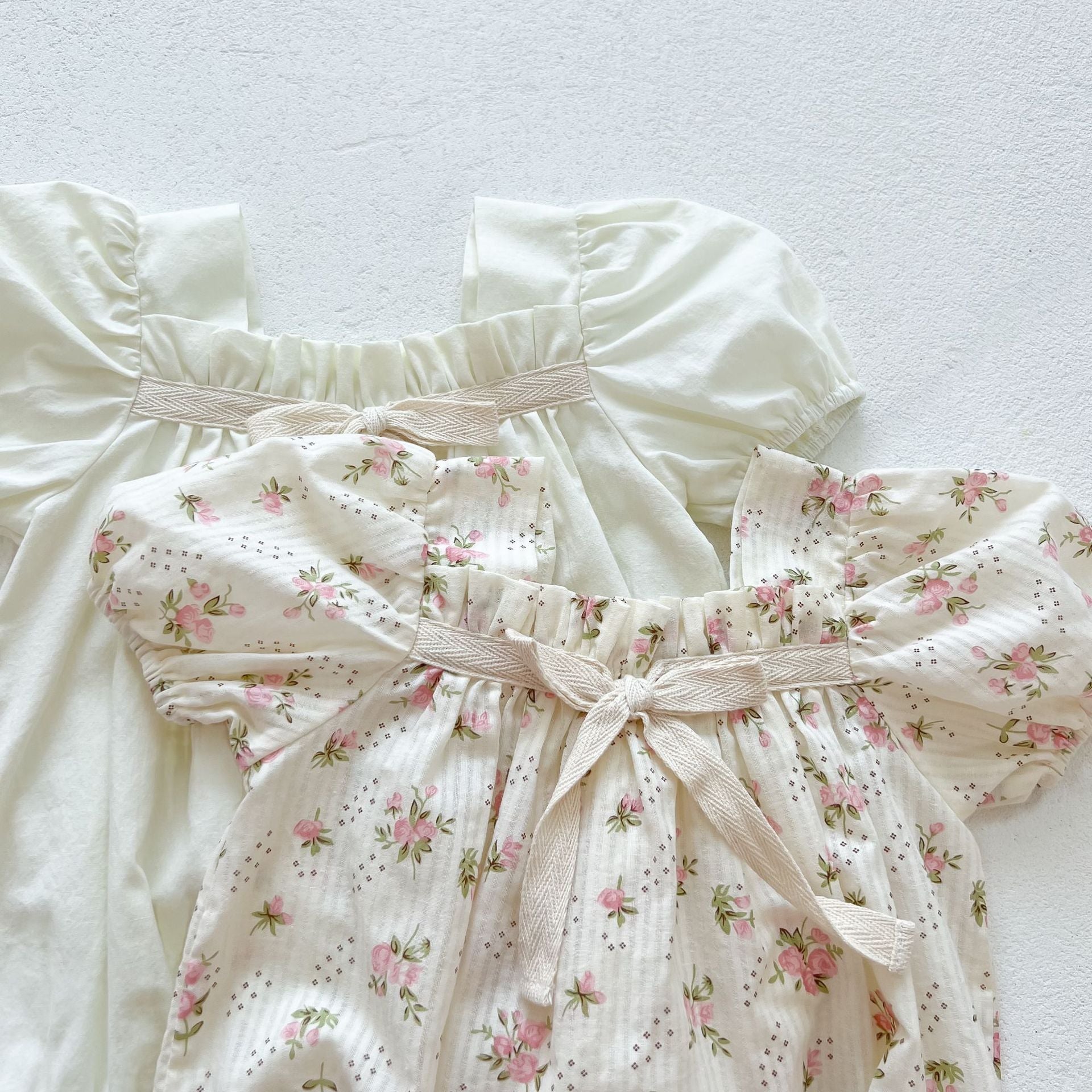 Baby girl onesie featuring a lovely bow-tie design, short sleeves, available in beige and apricot colors.