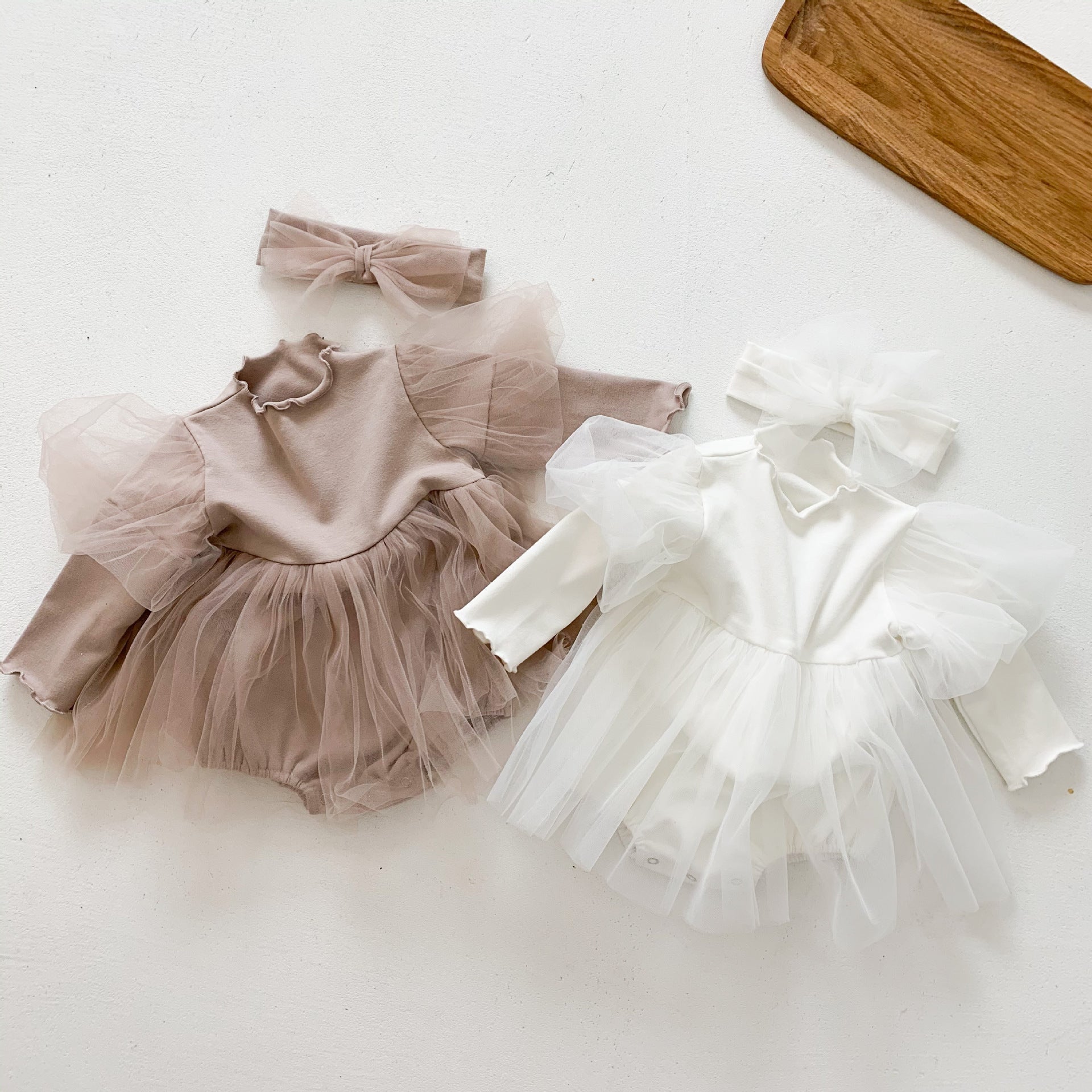 A stylish baby girl wearing a mesh tutu skirt with a solid top dress in white and purple, perfect for spring occasions.