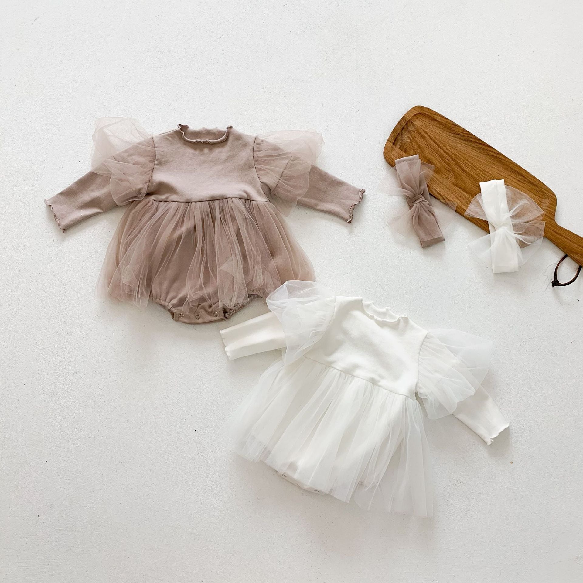 A stylish baby girl wearing a mesh tutu skirt with a solid top dress in white and purple, perfect for spring occasions.