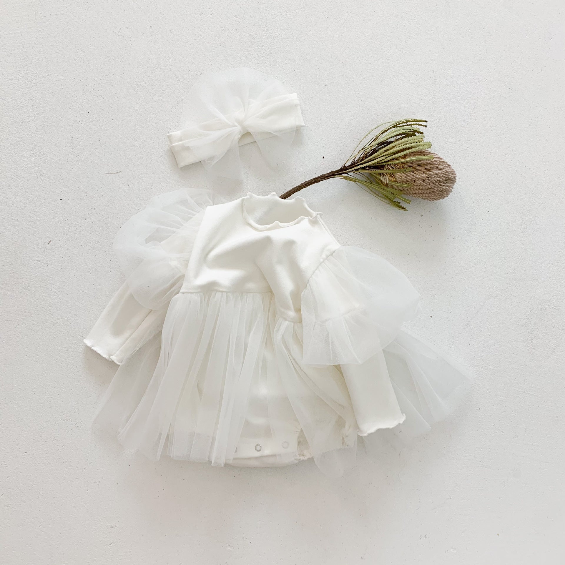 A stylish baby girl wearing a mesh tutu skirt with a solid top dress in white and purple, perfect for spring occasions.