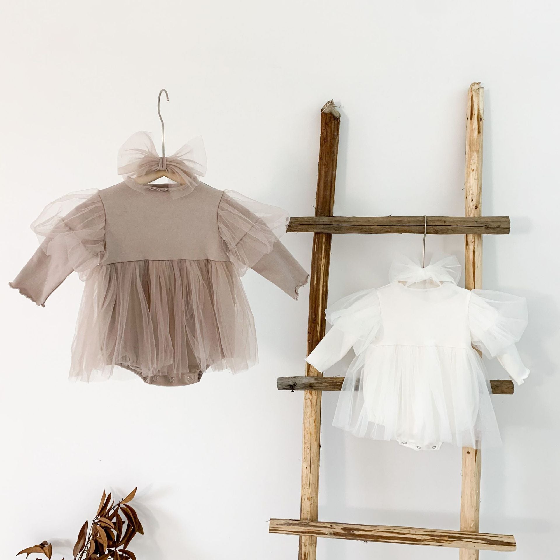 A stylish baby girl wearing a mesh tutu skirt with a solid top dress in white and purple, perfect for spring occasions.