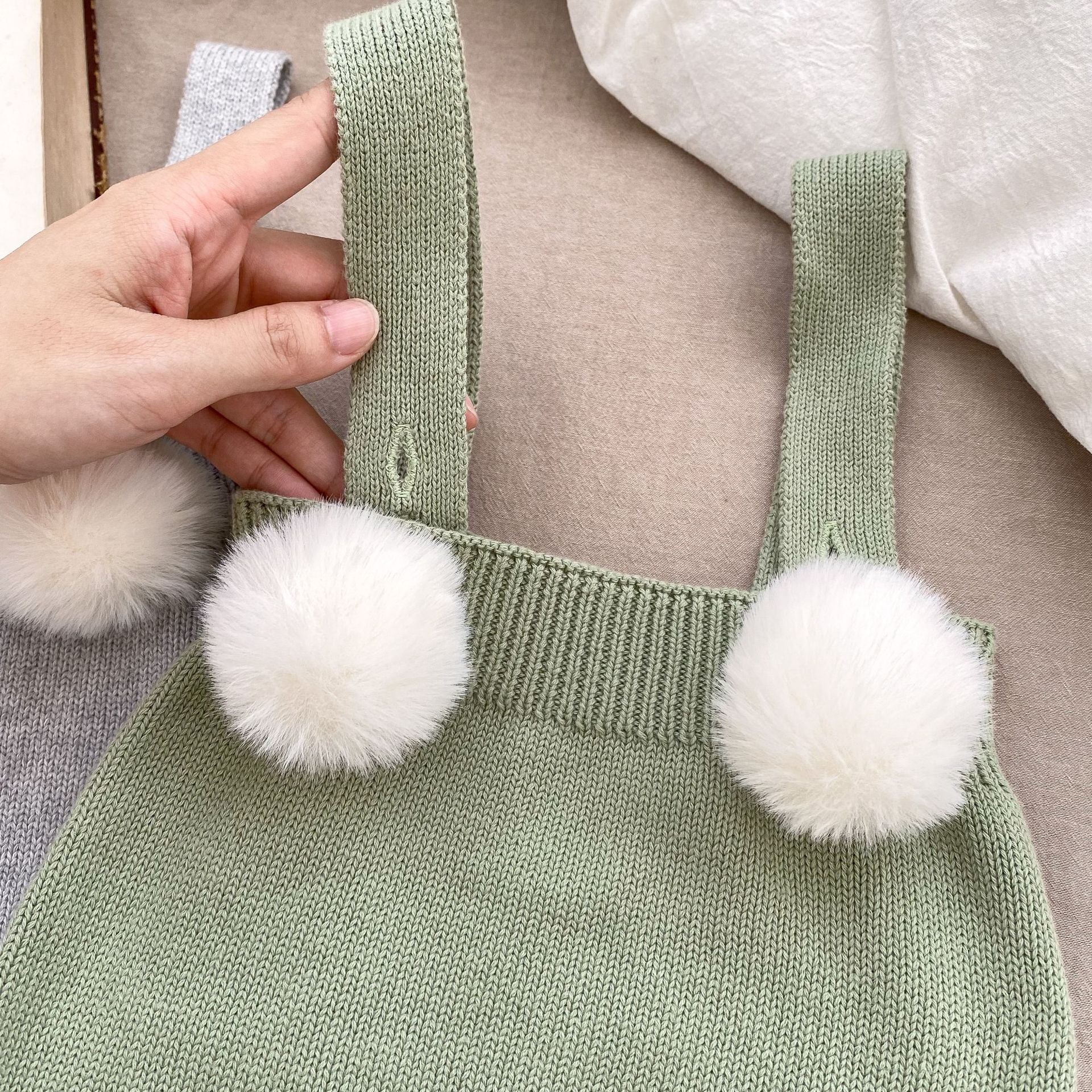 Baby girl wearing a plush ball camisole knitted vest in green, showcasing its soft cotton material and stylish design.